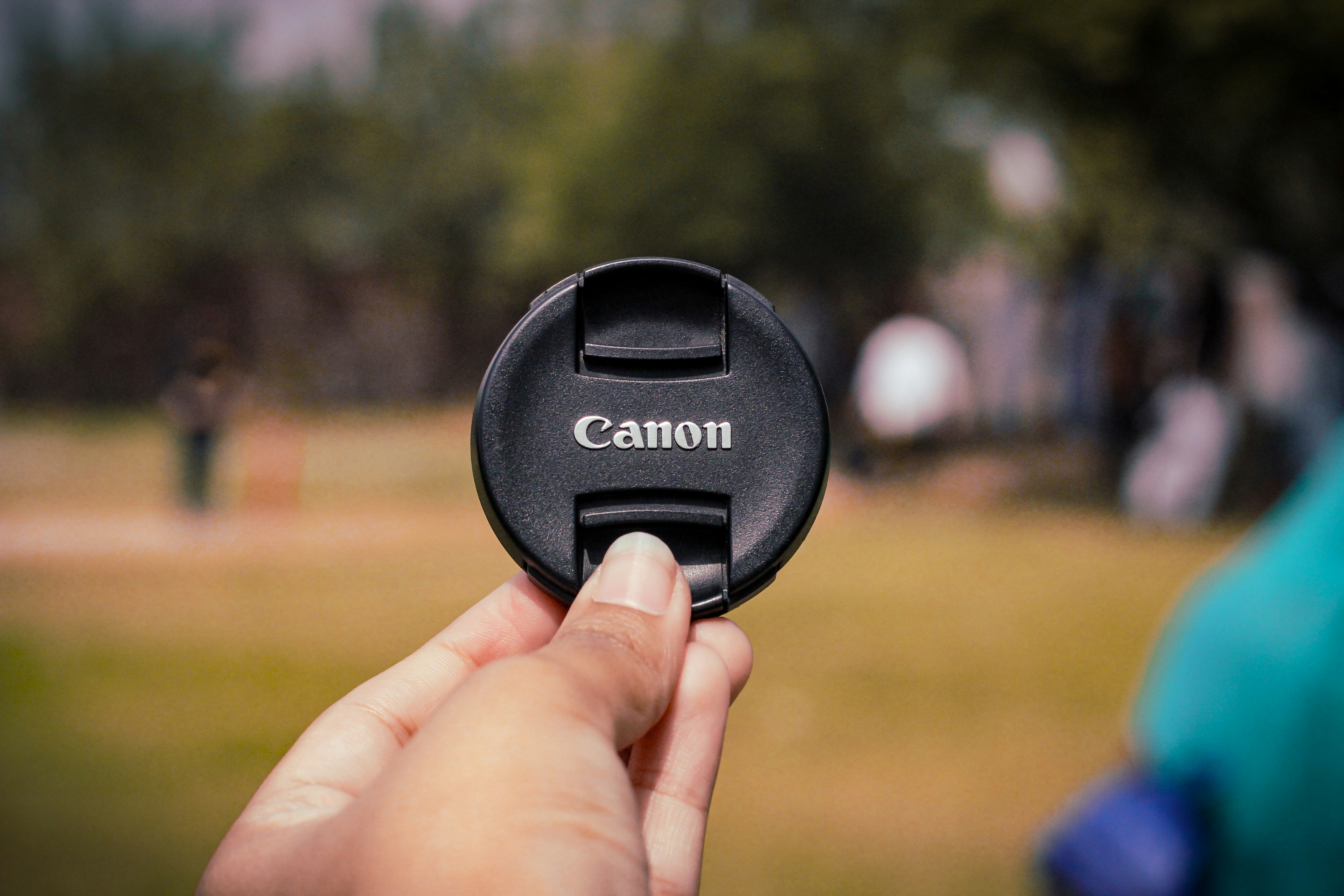 a person holding a camera lens cap in their hand