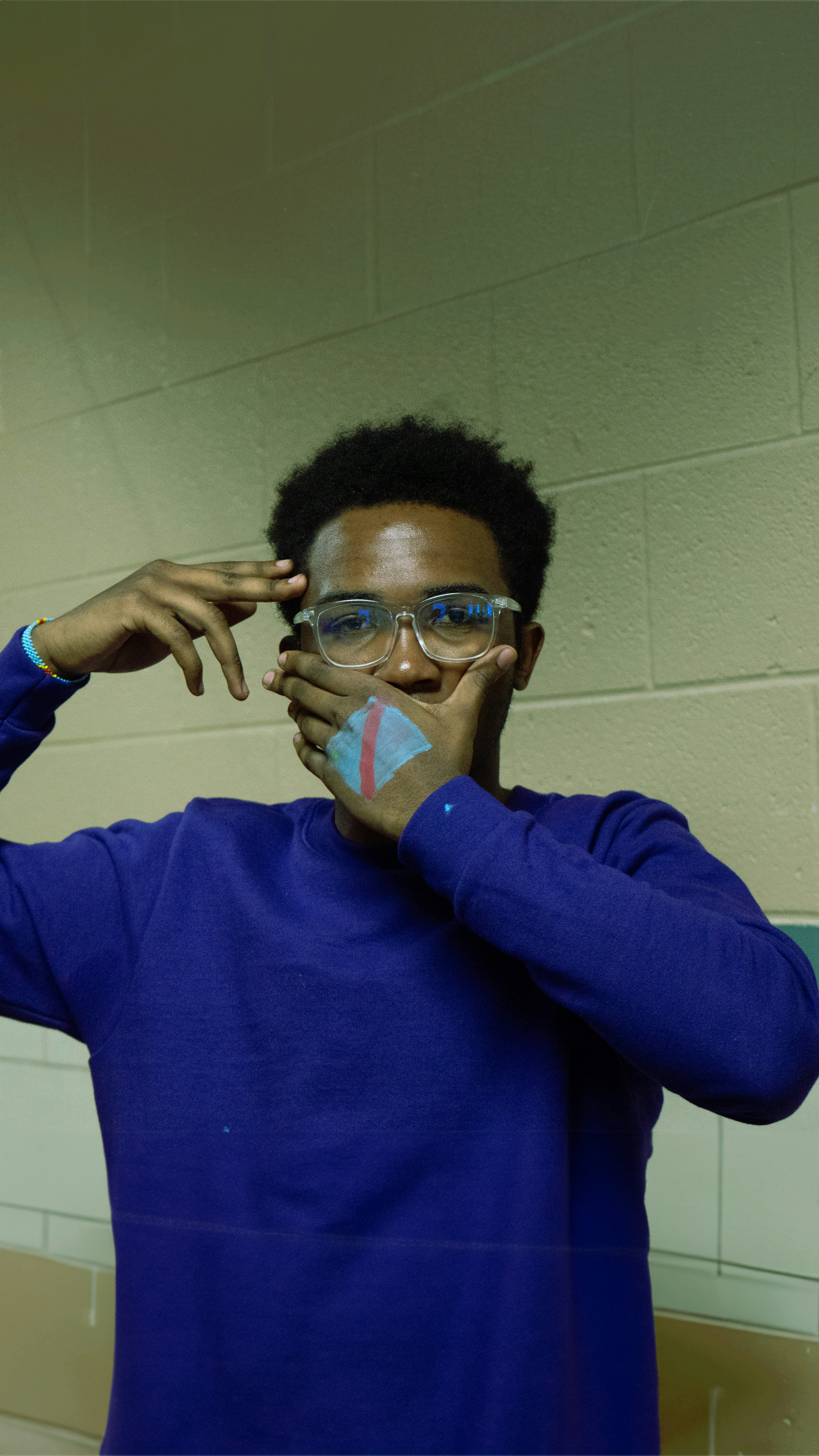a man in a blue shirt holding his hands to his face
