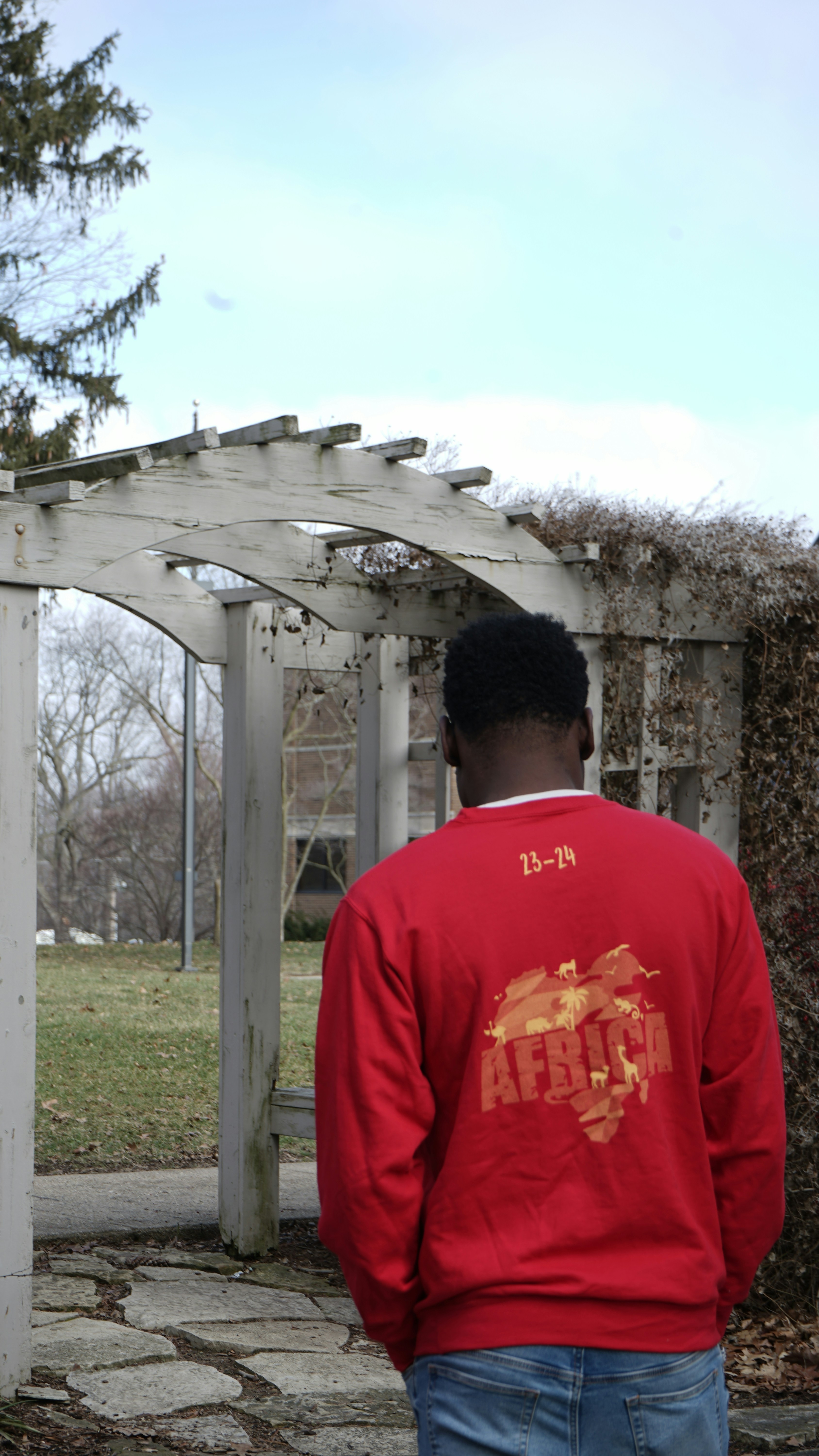 a man in a red jacket standing in front of a wooden structure