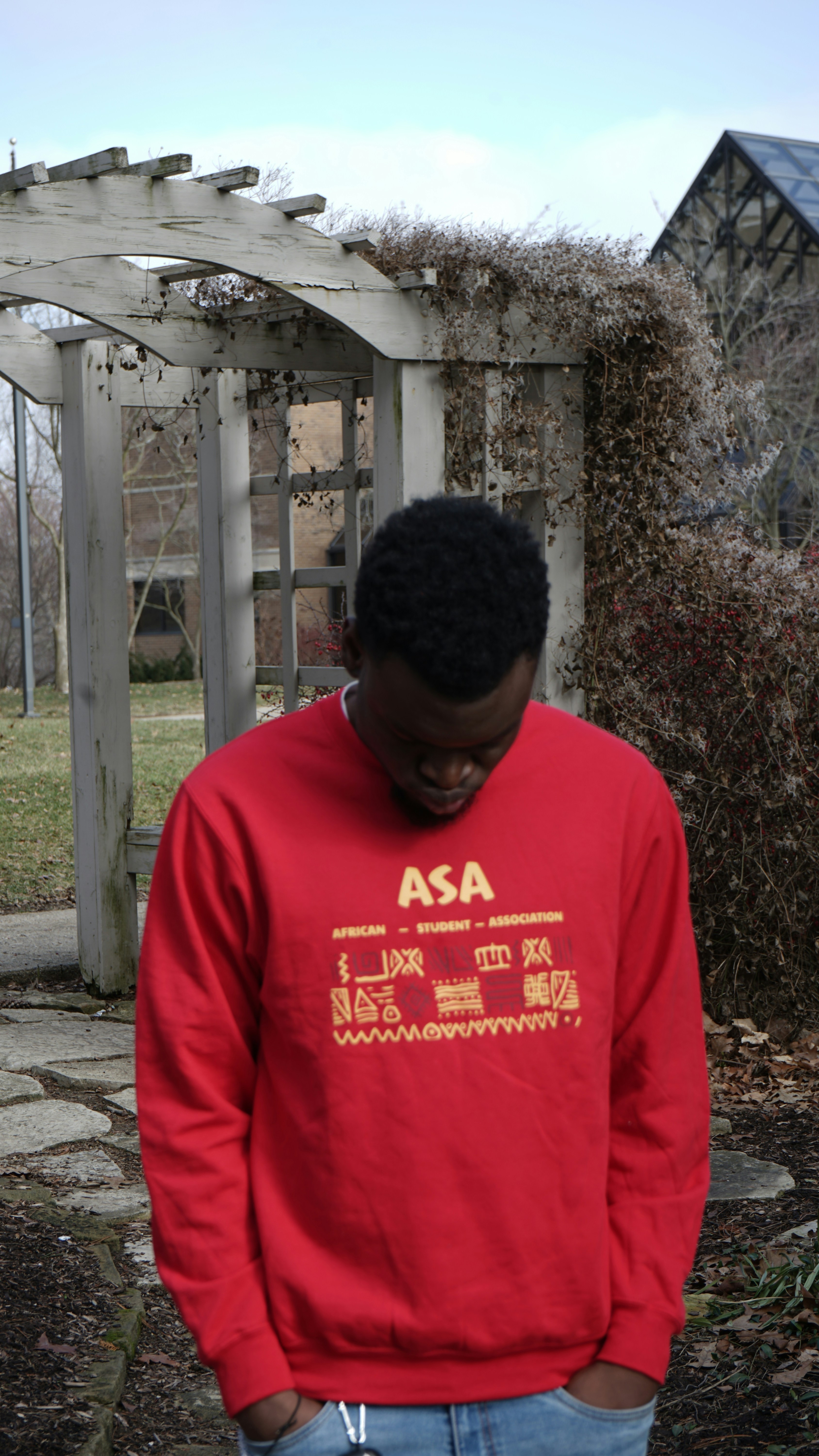 a man in a red sweatshirt standing in front of a gazebo