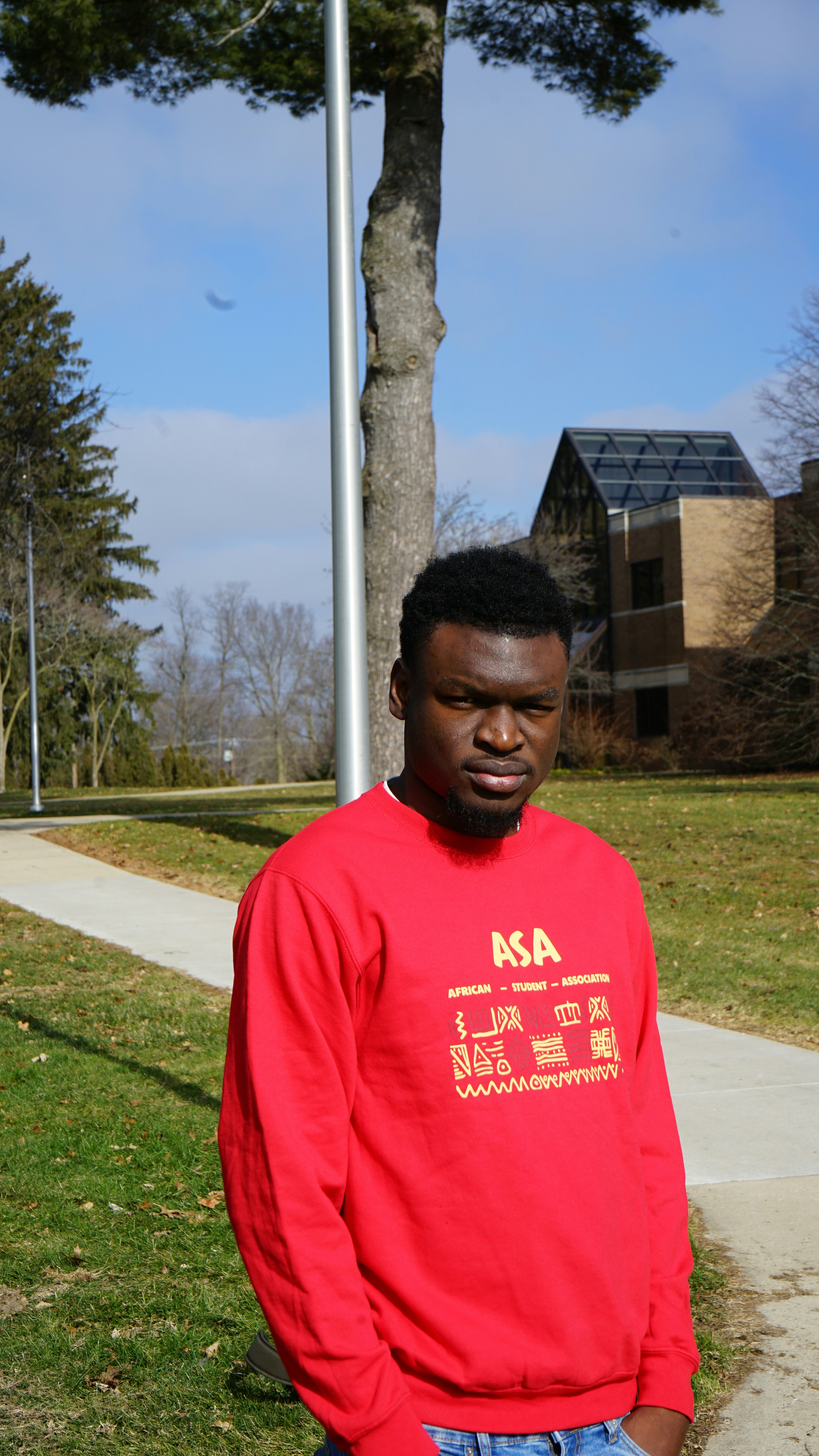 a man in a red shirt standing in front of a tree