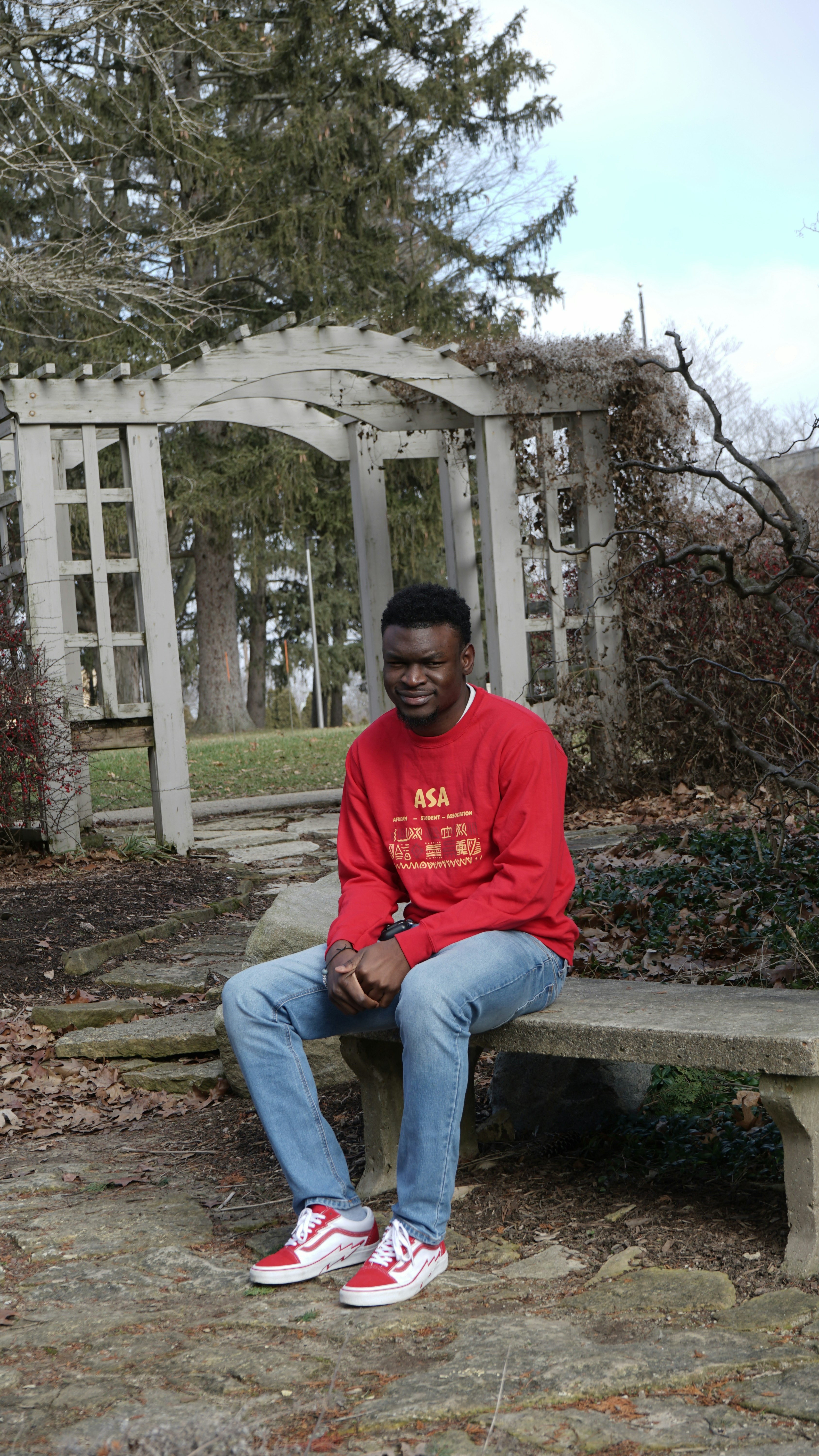 a man in a red sweatshirt is sitting on a bench