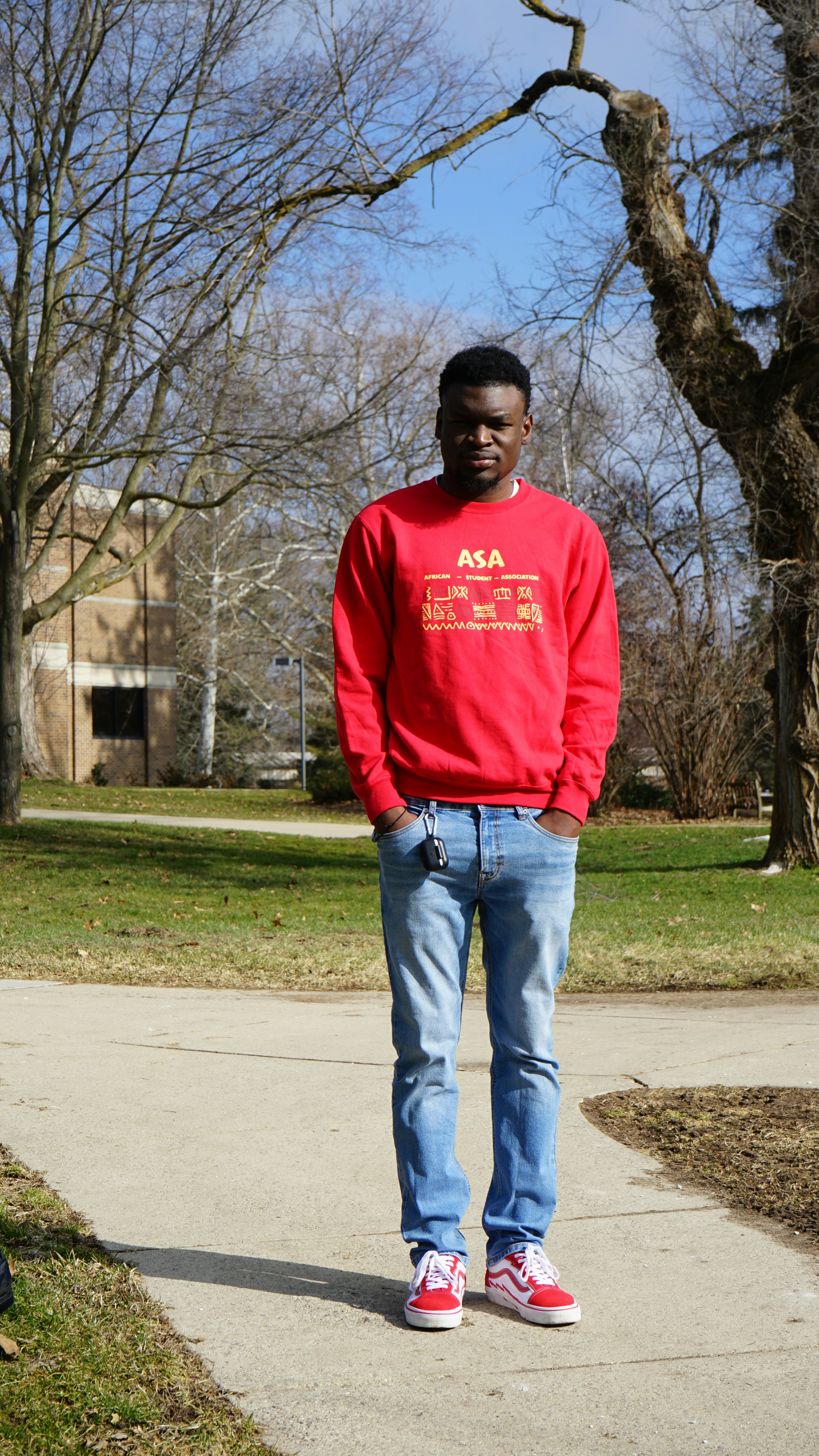 a man in a red sweatshirt standing on a sidewalk