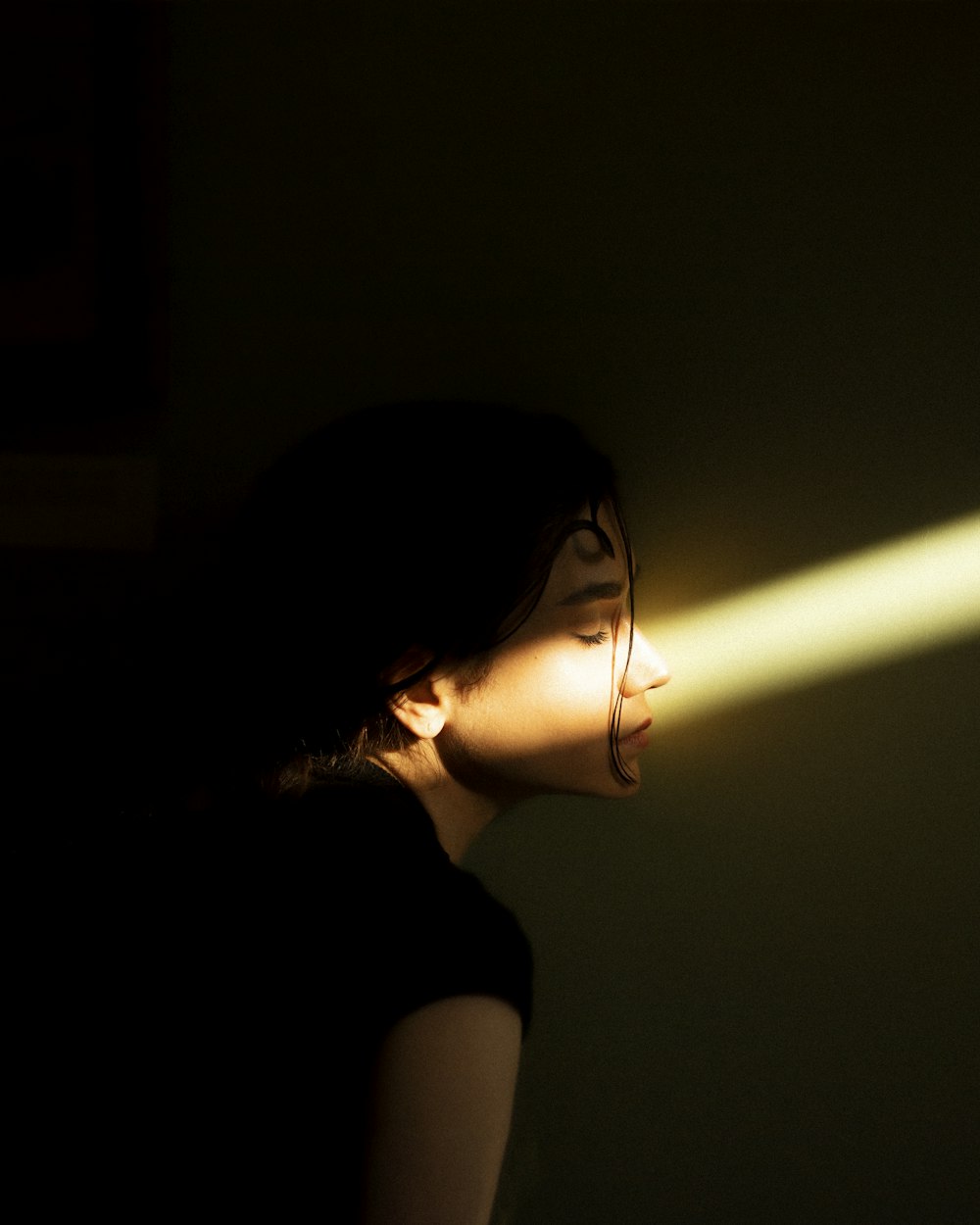 a woman standing in a dark room with a light coming through her eyes