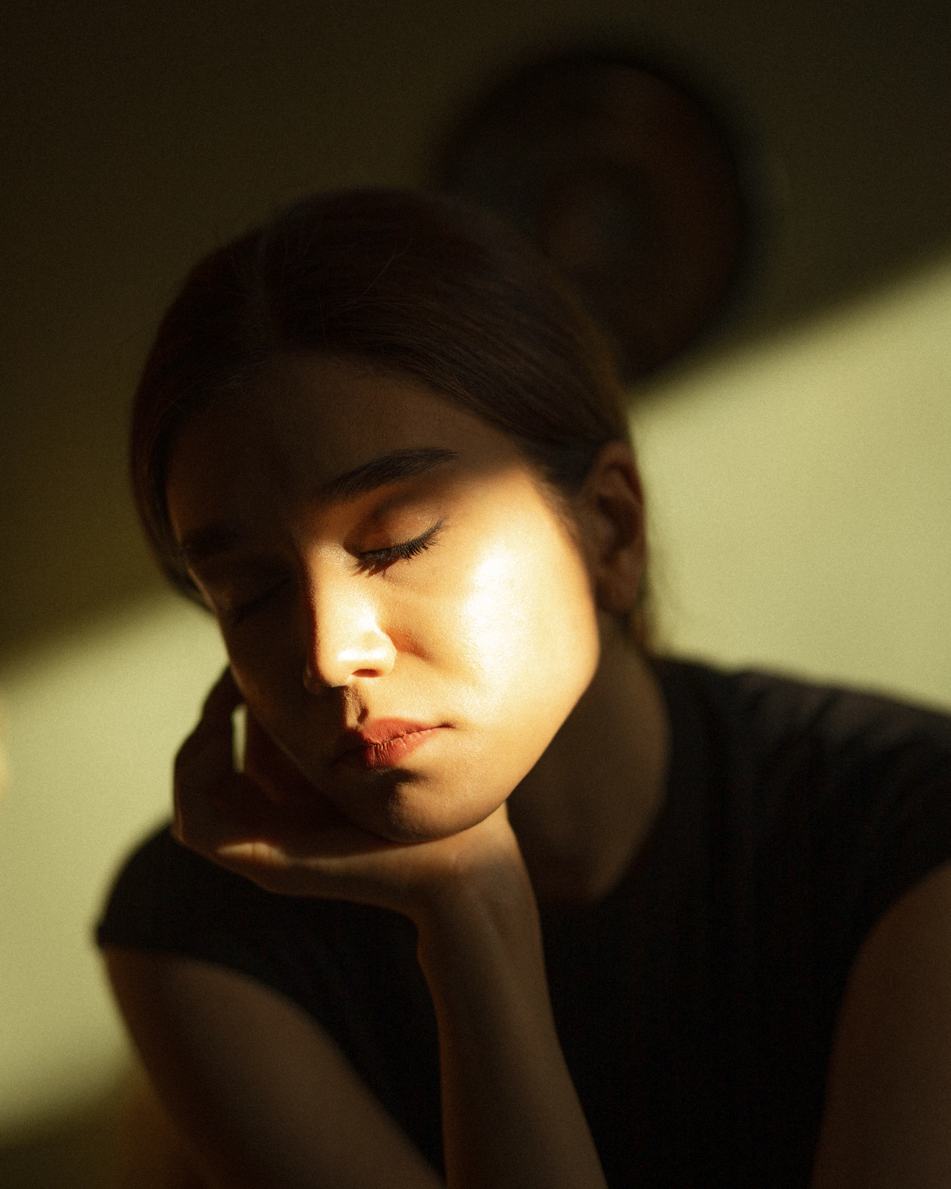 a woman sitting in a dark room with her eyes closed