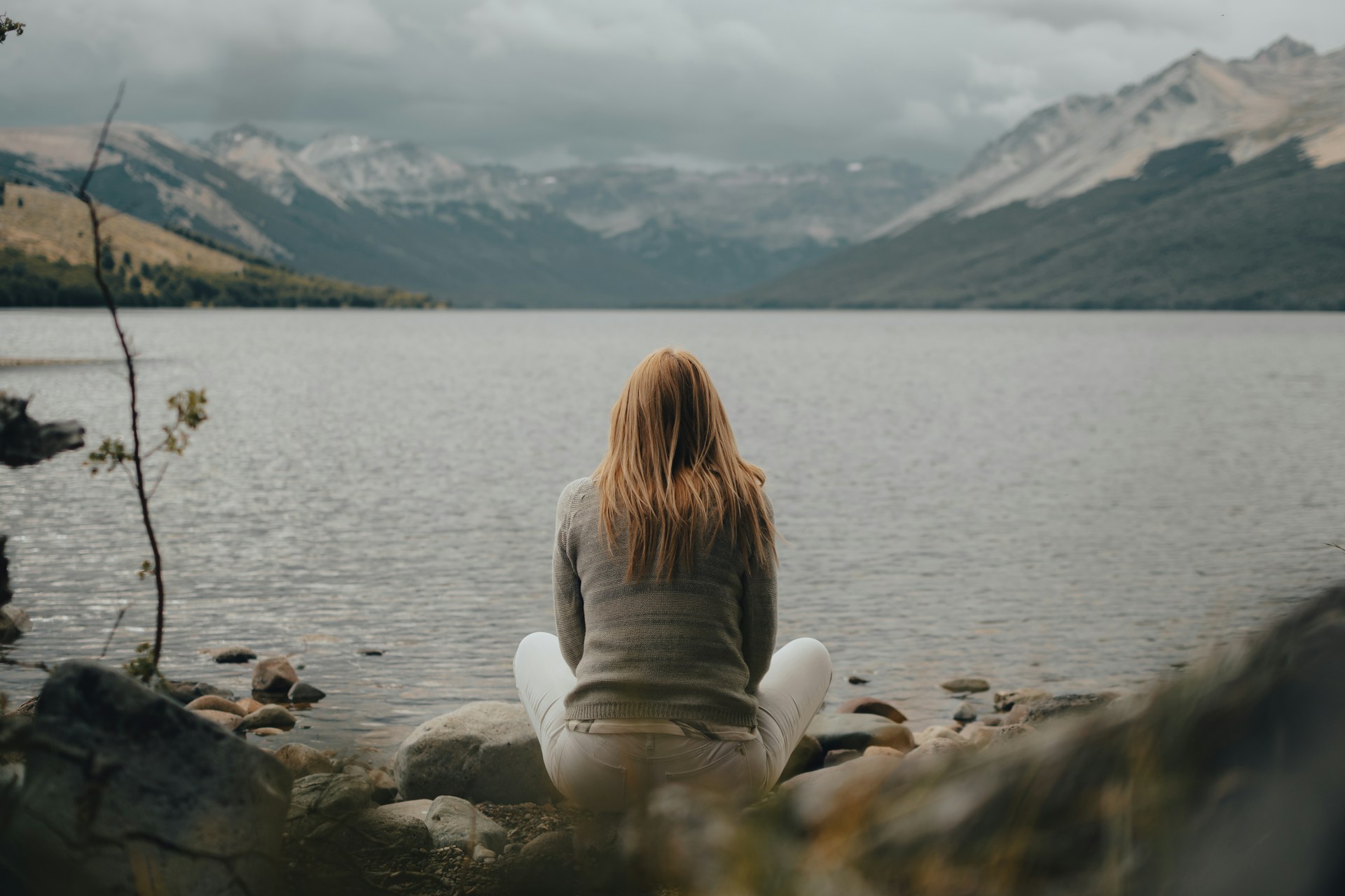 a woman sitting on a rock near a body of water