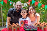 a man and woman pose with a child in front of a cake