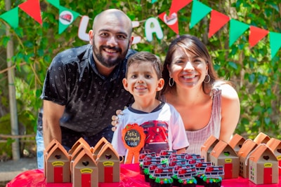 a man and woman pose with a child in front of a cake