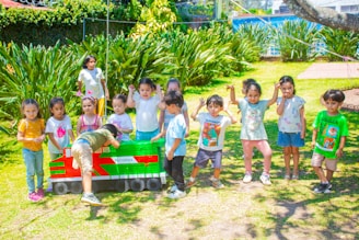 a group of children standing in front of a toy train