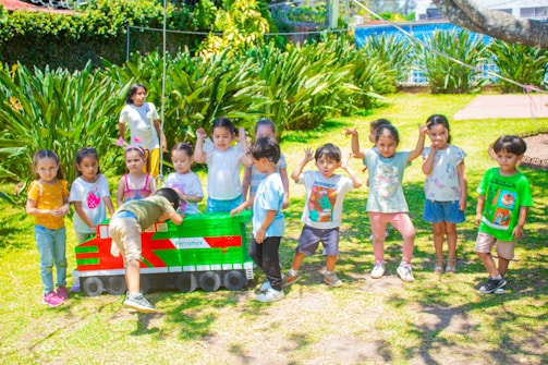 a group of children standing in front of a toy train