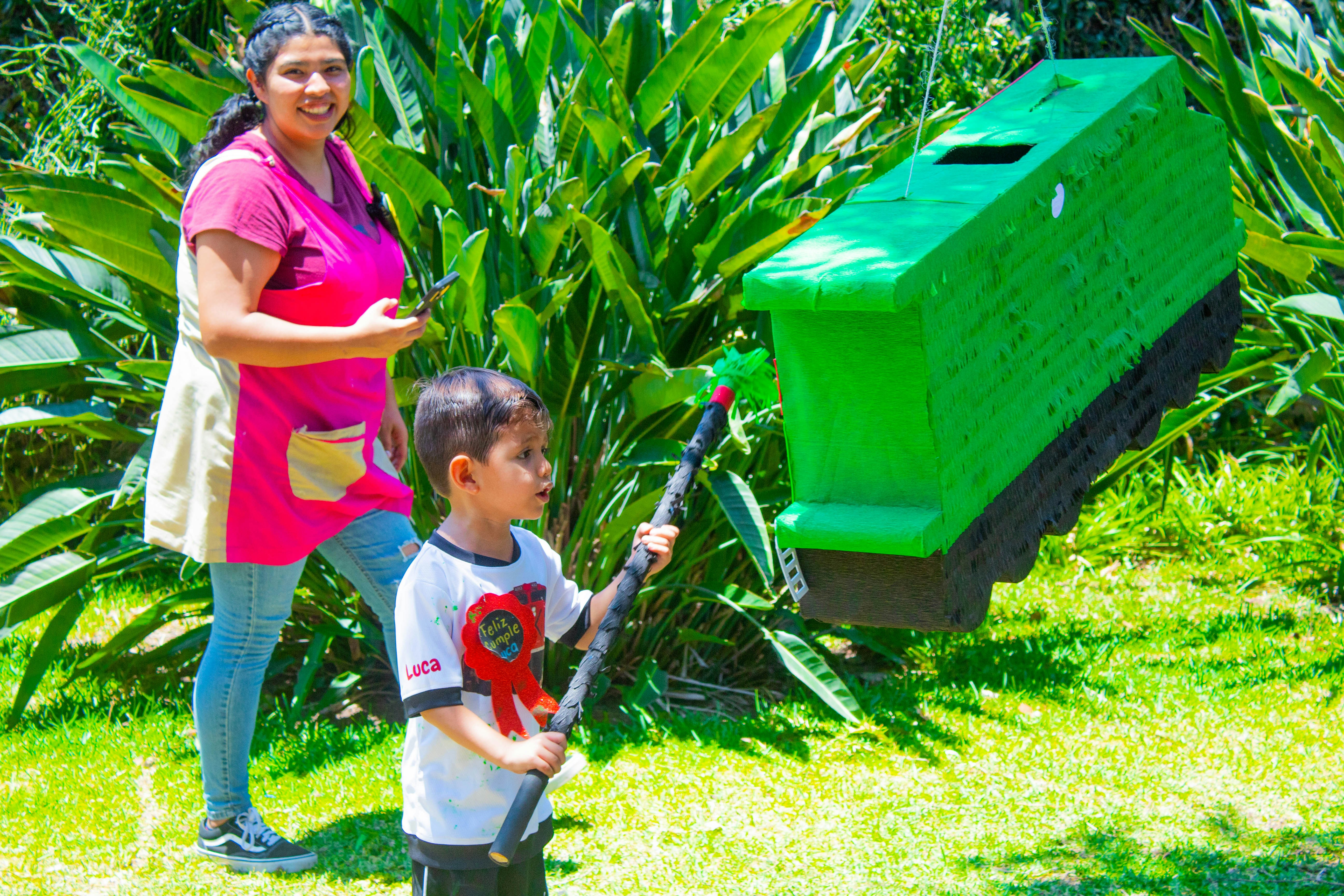 a woman standing next to a boy holding a bat
