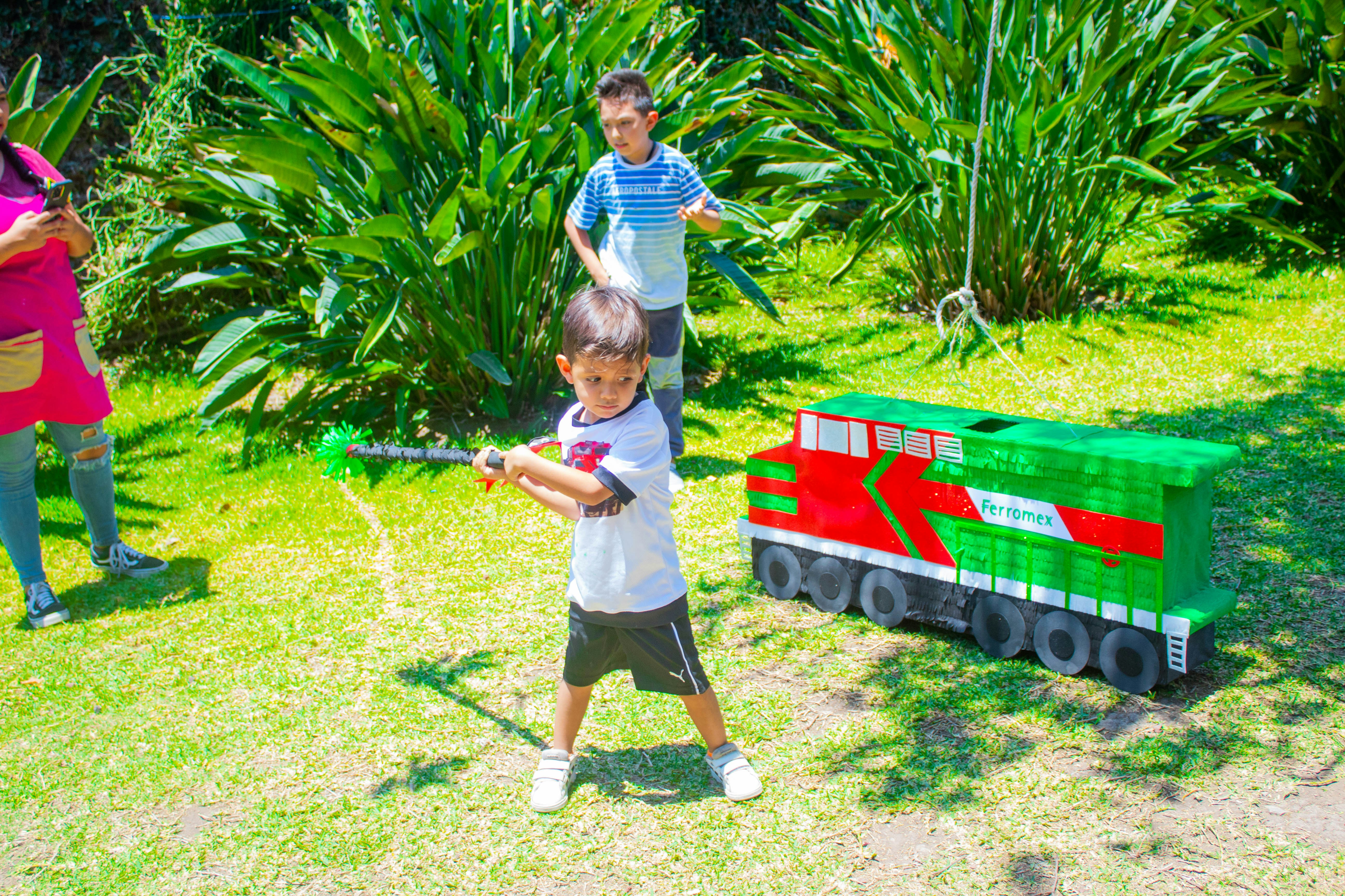 a young boy holding a baseball bat next to a toy train