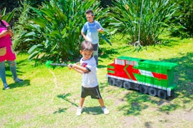 a young boy holding a baseball bat next to a toy train