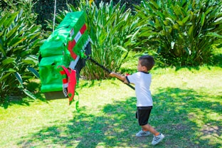 a young boy holding onto a kite in a yard