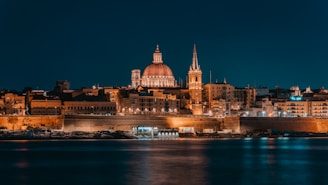 a night view of a large city with a cathedral in Valletta Malta
