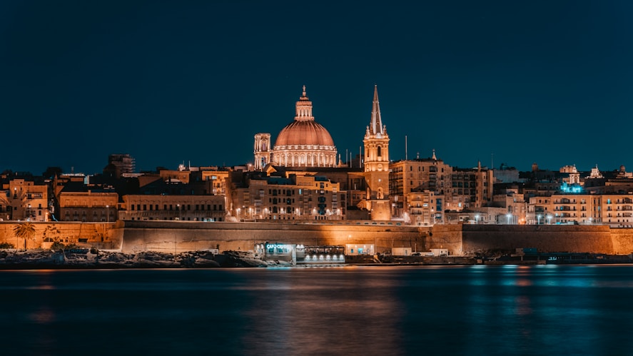 a night view of a large city with a cathedral in Valletta Malta