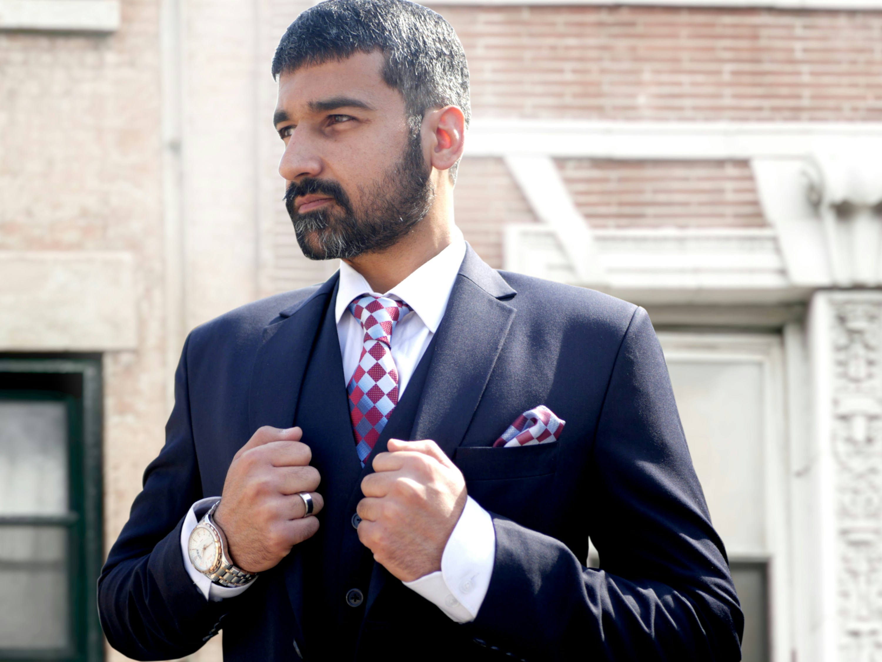 A man wearing a suit and tie standing in front of a building