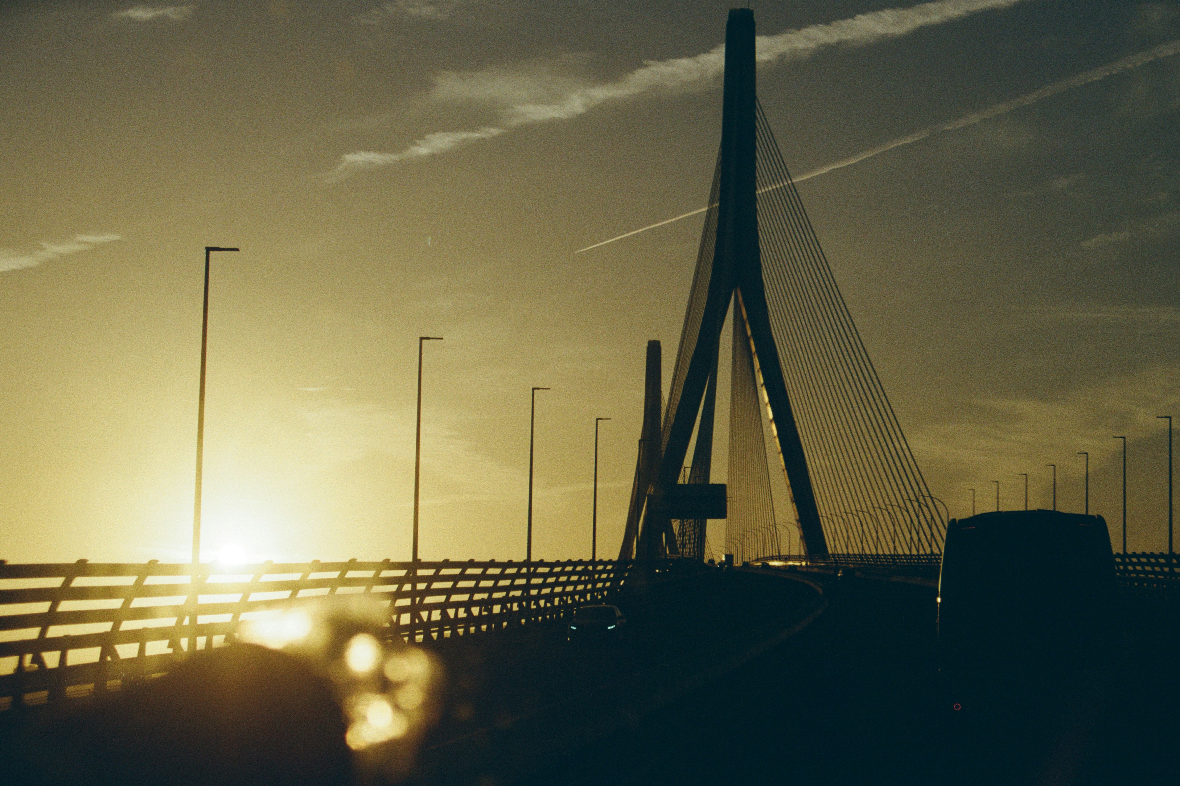 the sun is setting over a bridge with traffic