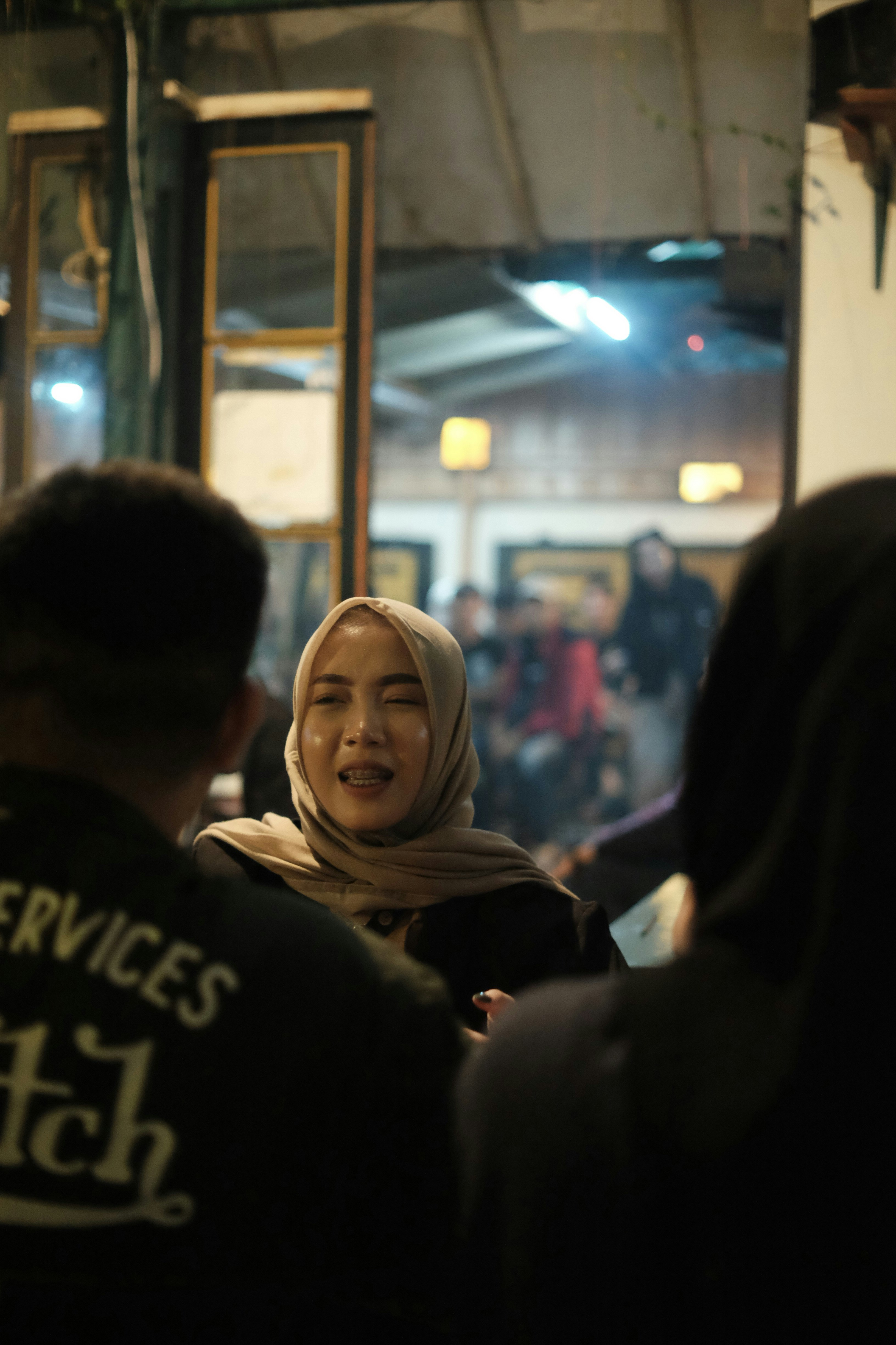 Young woman with hijab, warm indoor lighting, friendly smile