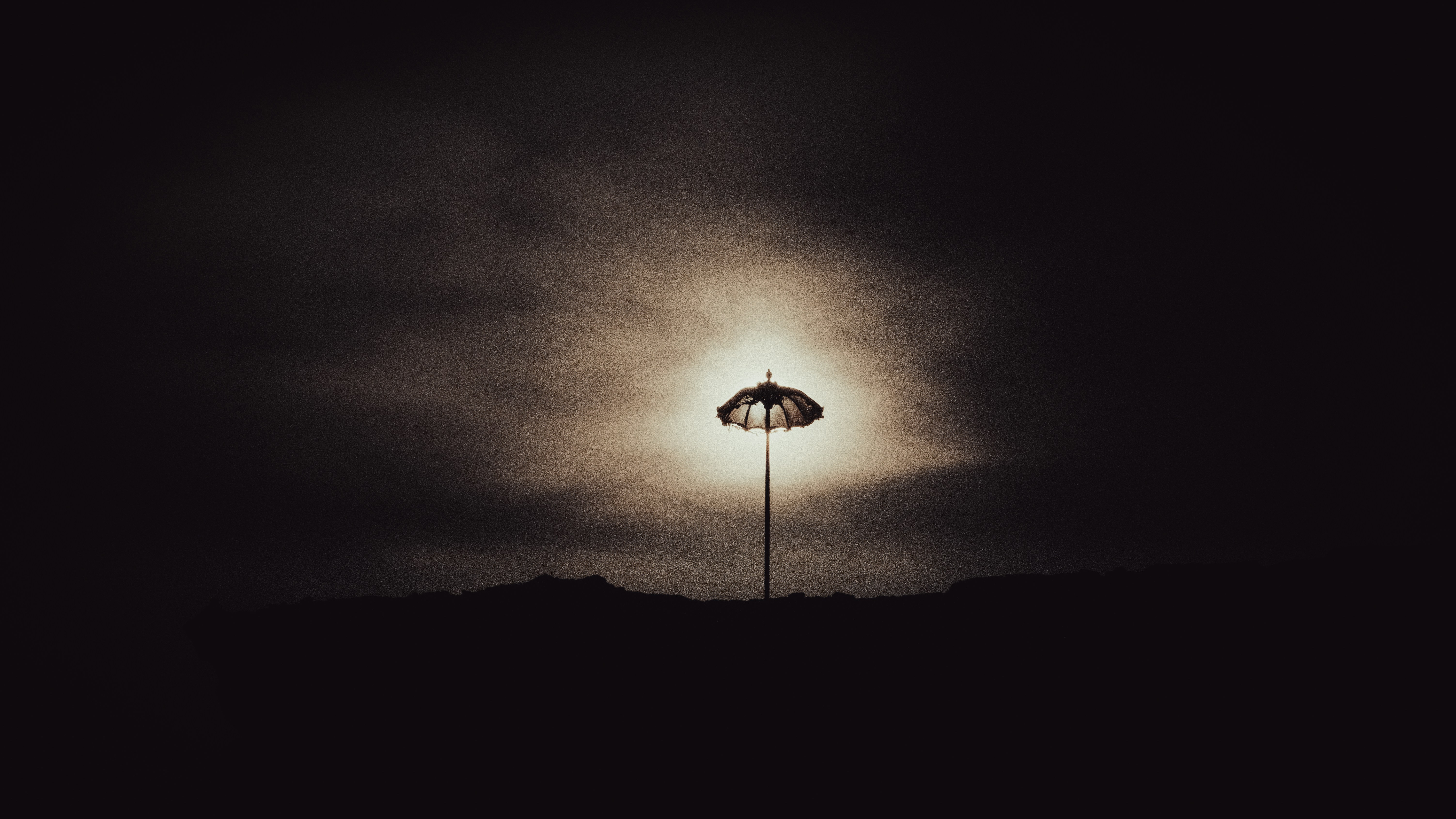 un lampione seduto in cima a una collina sotto un cielo nuvoloso