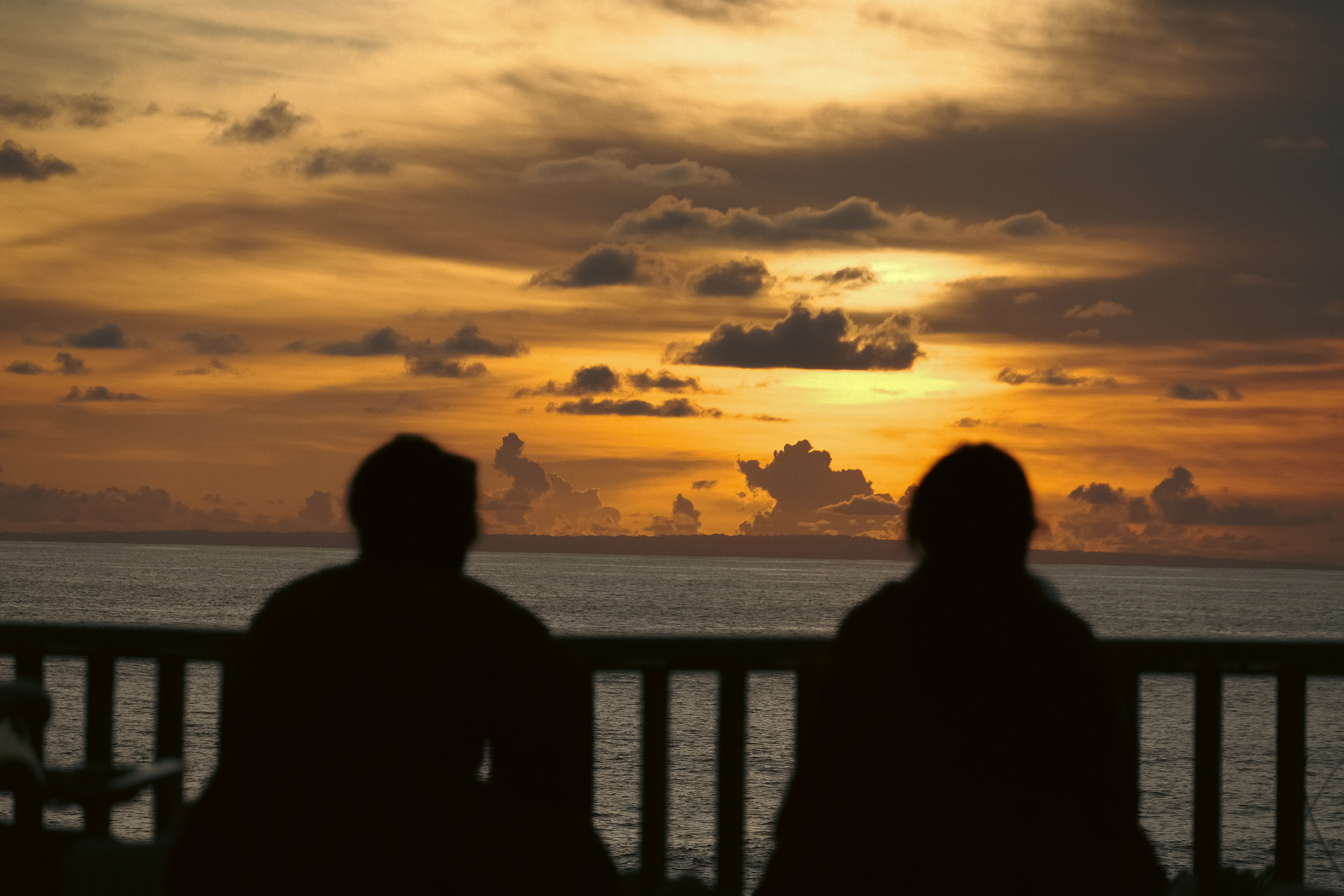 Due persone sedute su un balcone che guardano il tramonto