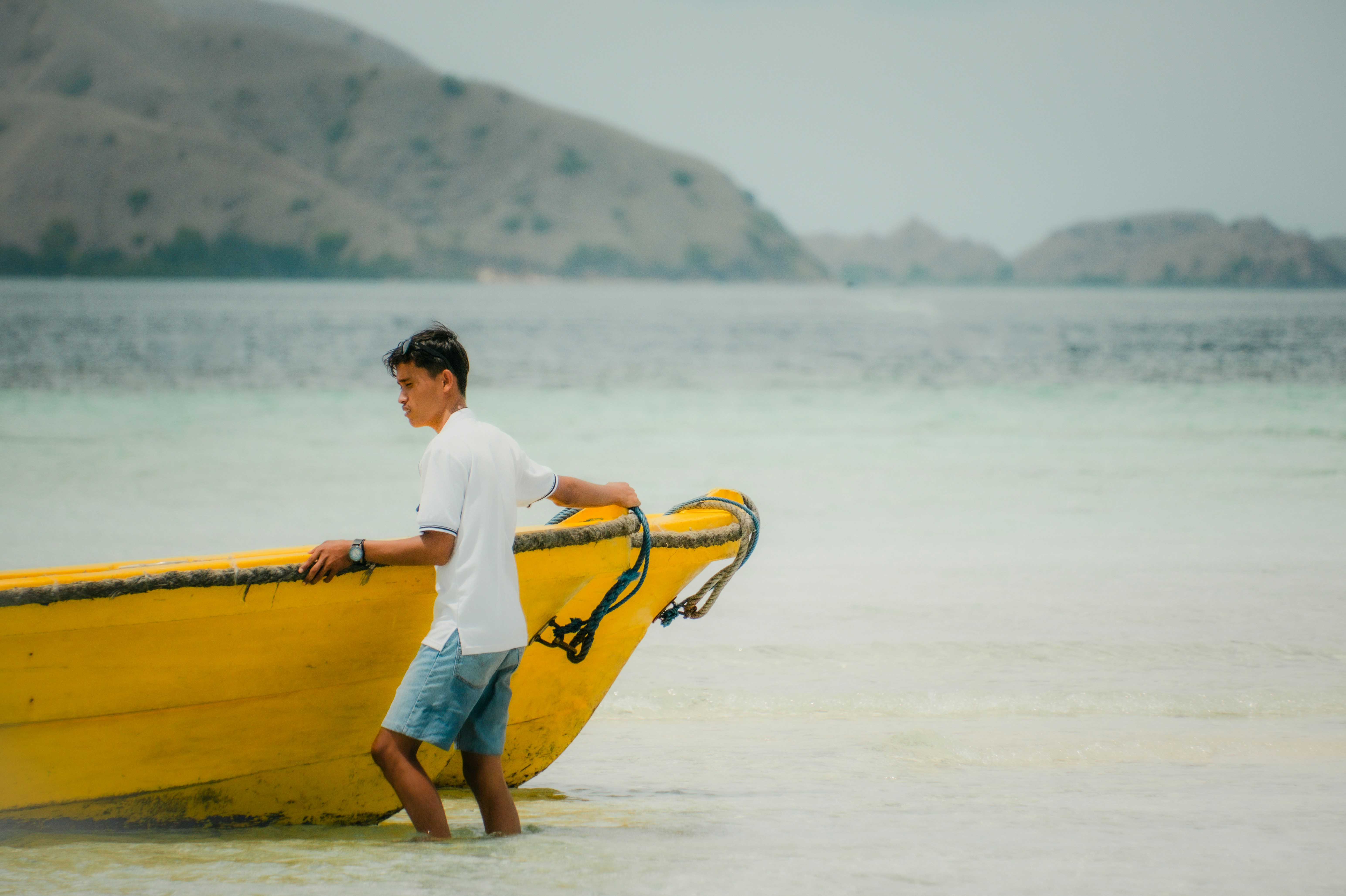un uomo in piedi accanto a una barca gialla nell'acqua