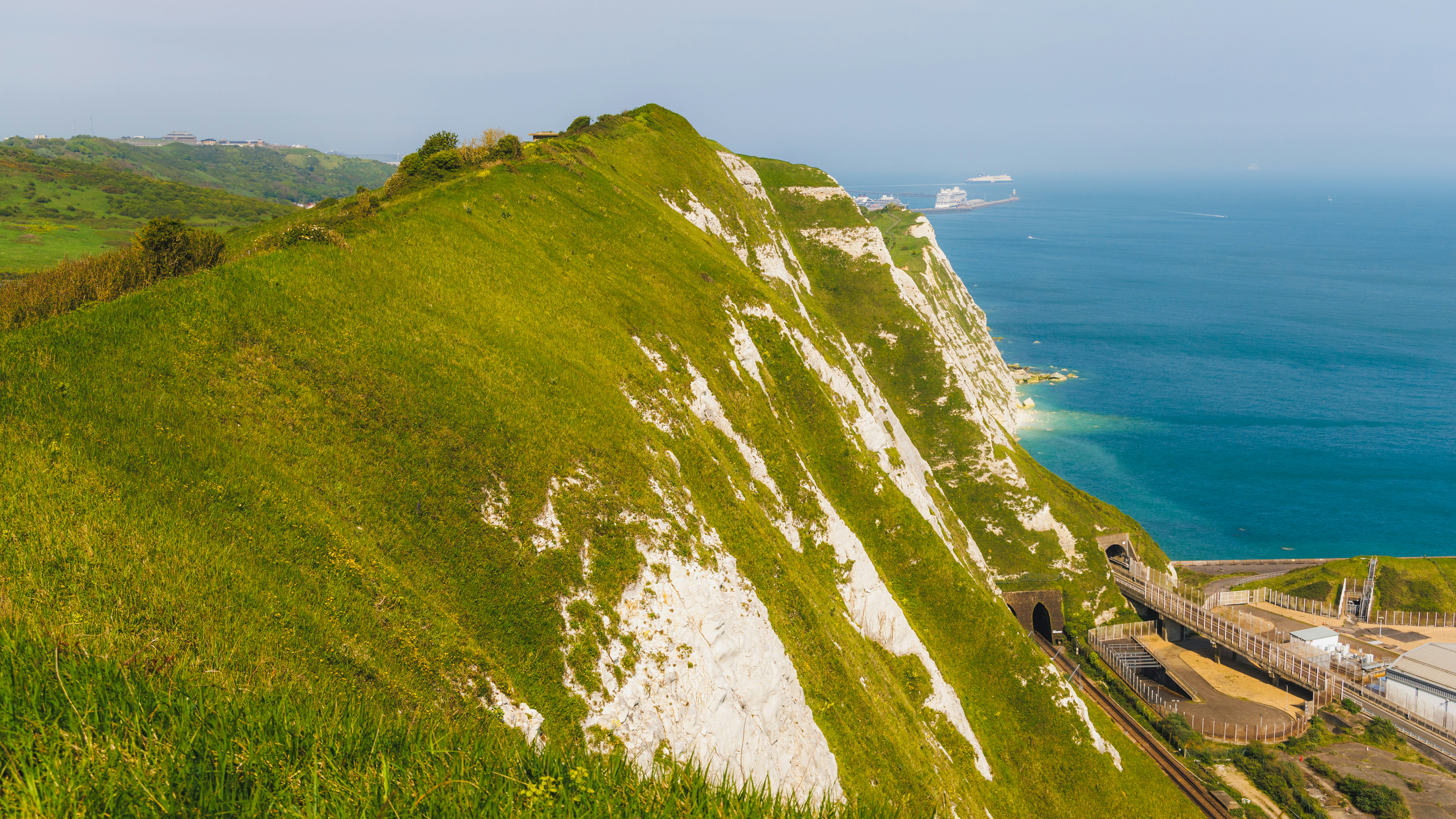 a grassy hill with a large body of water in the background
