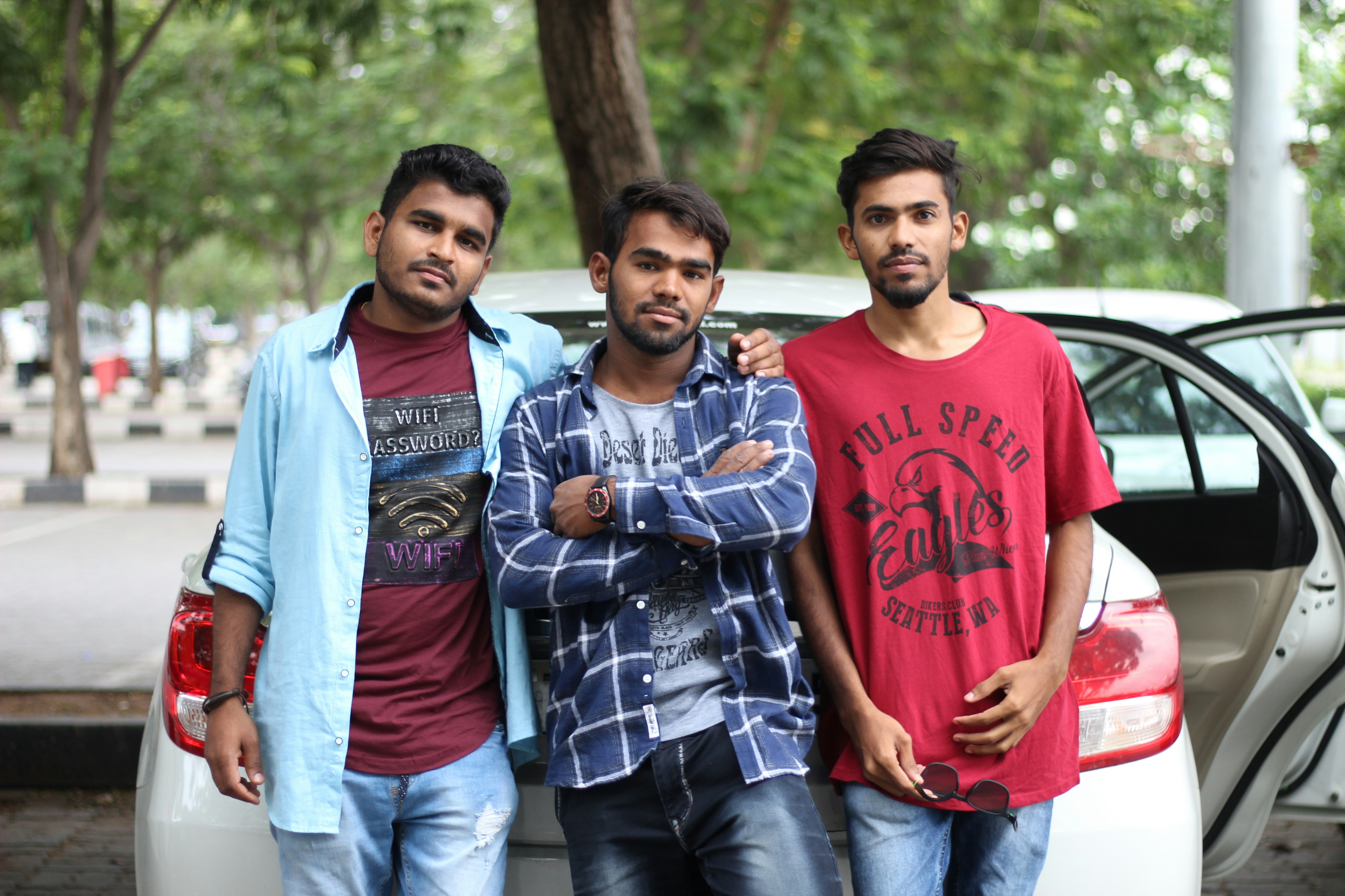 three men standing next to each other in front of a car