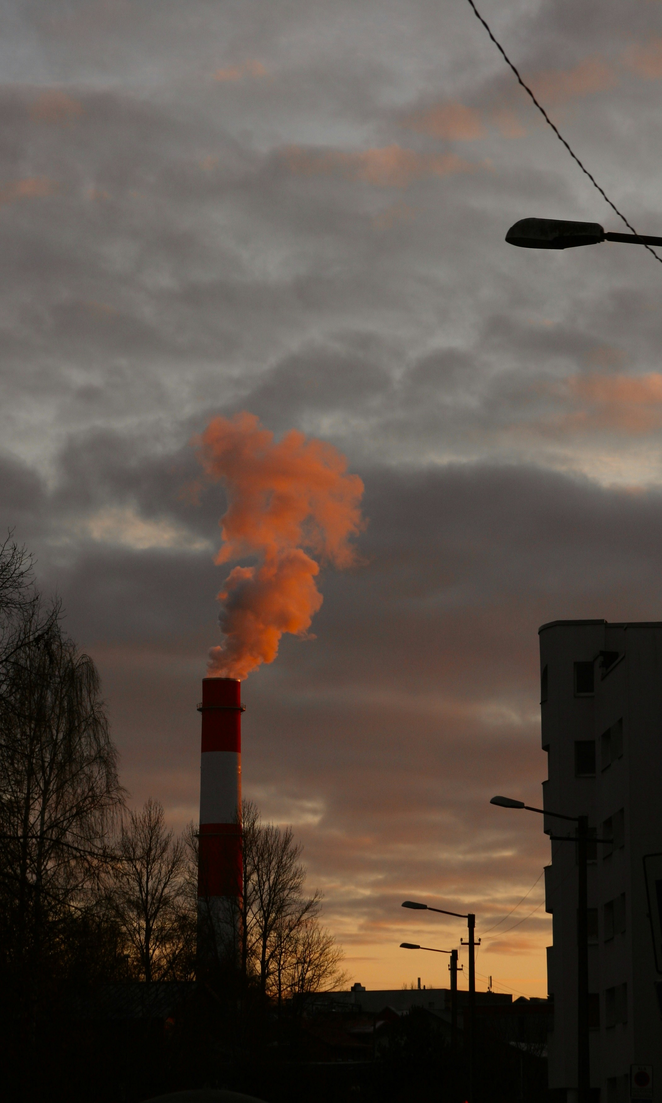 a red and white smokestack emits from a building