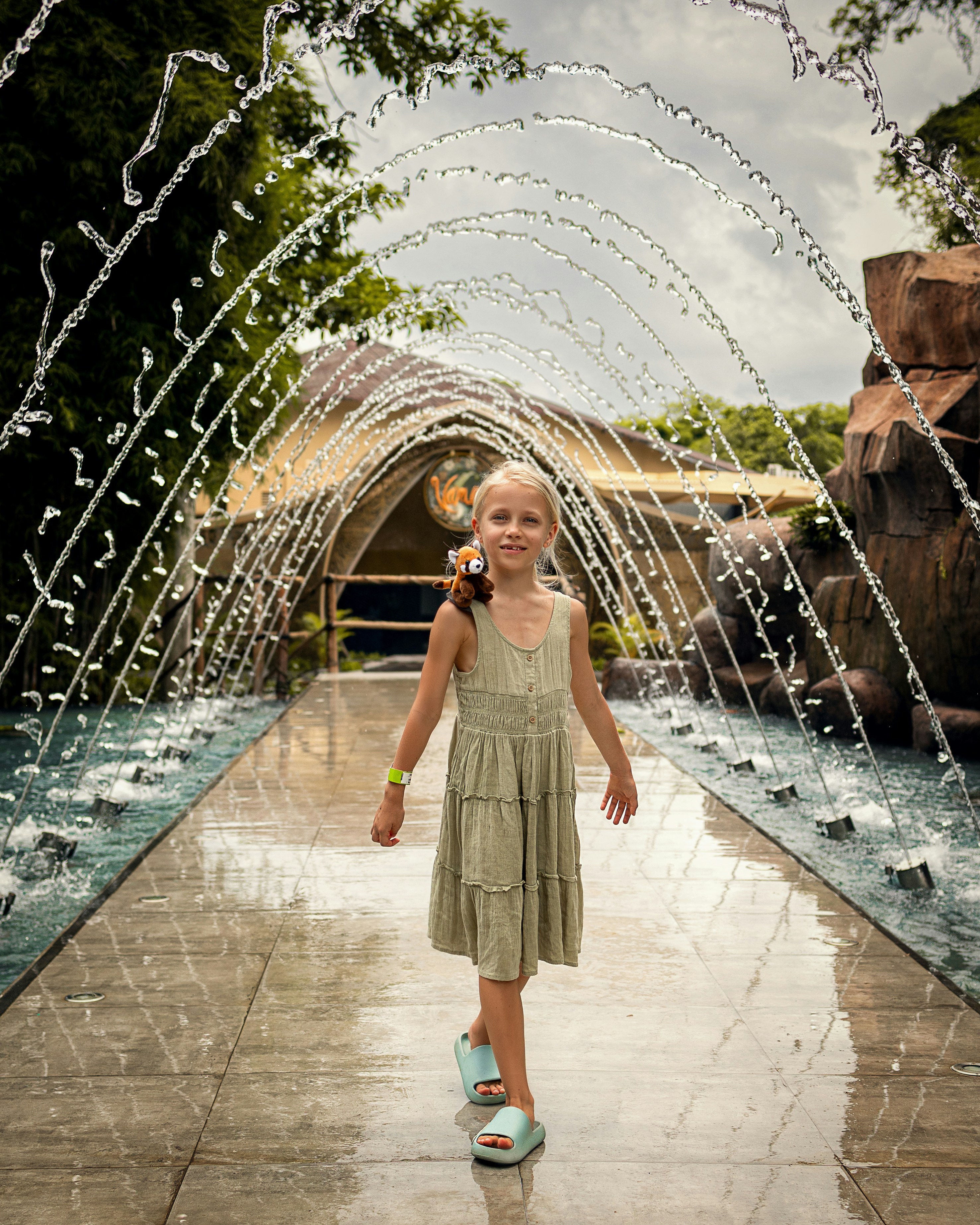 a little girl standing in front of a fountain