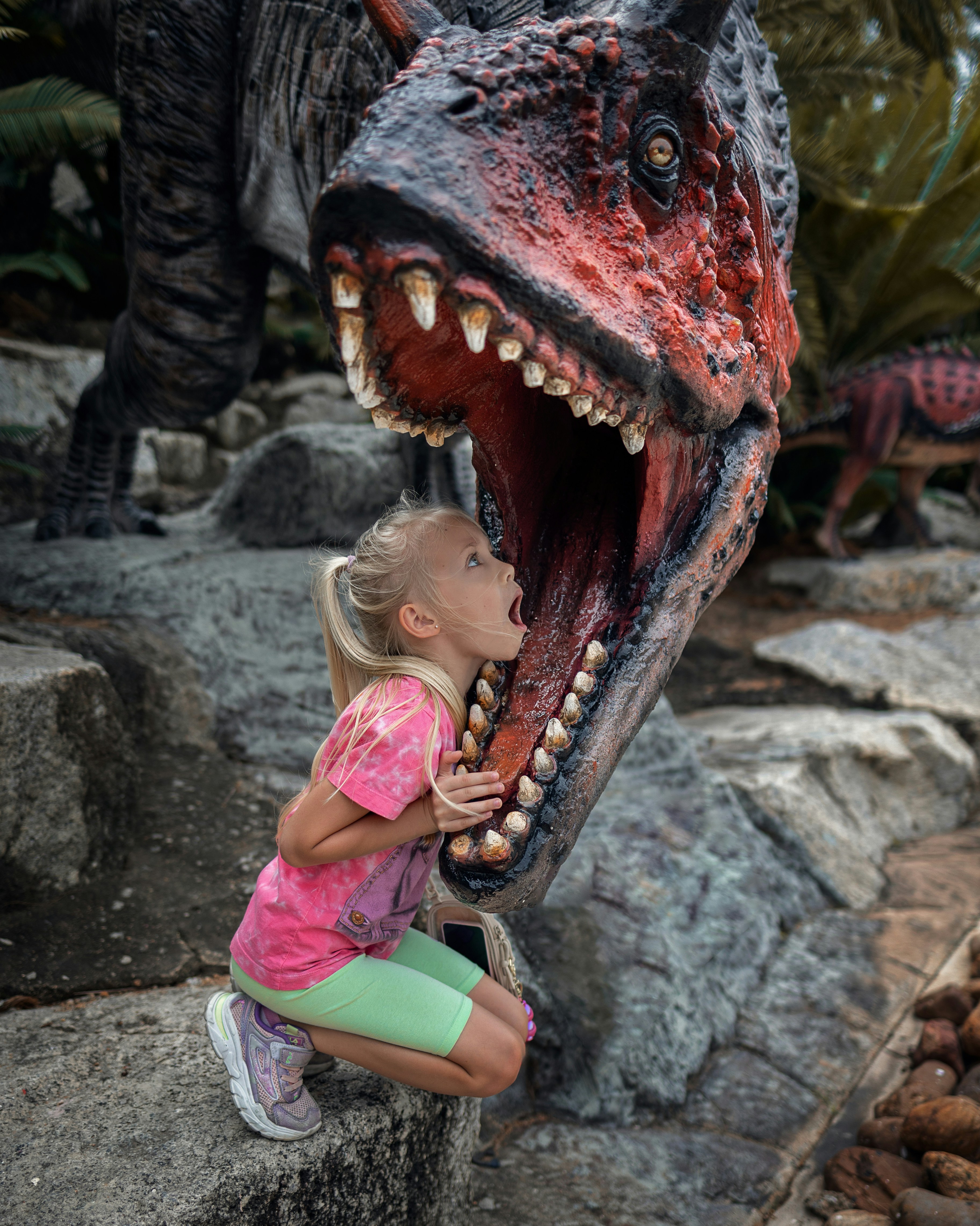 a little girl playing with a fake dinosaur
