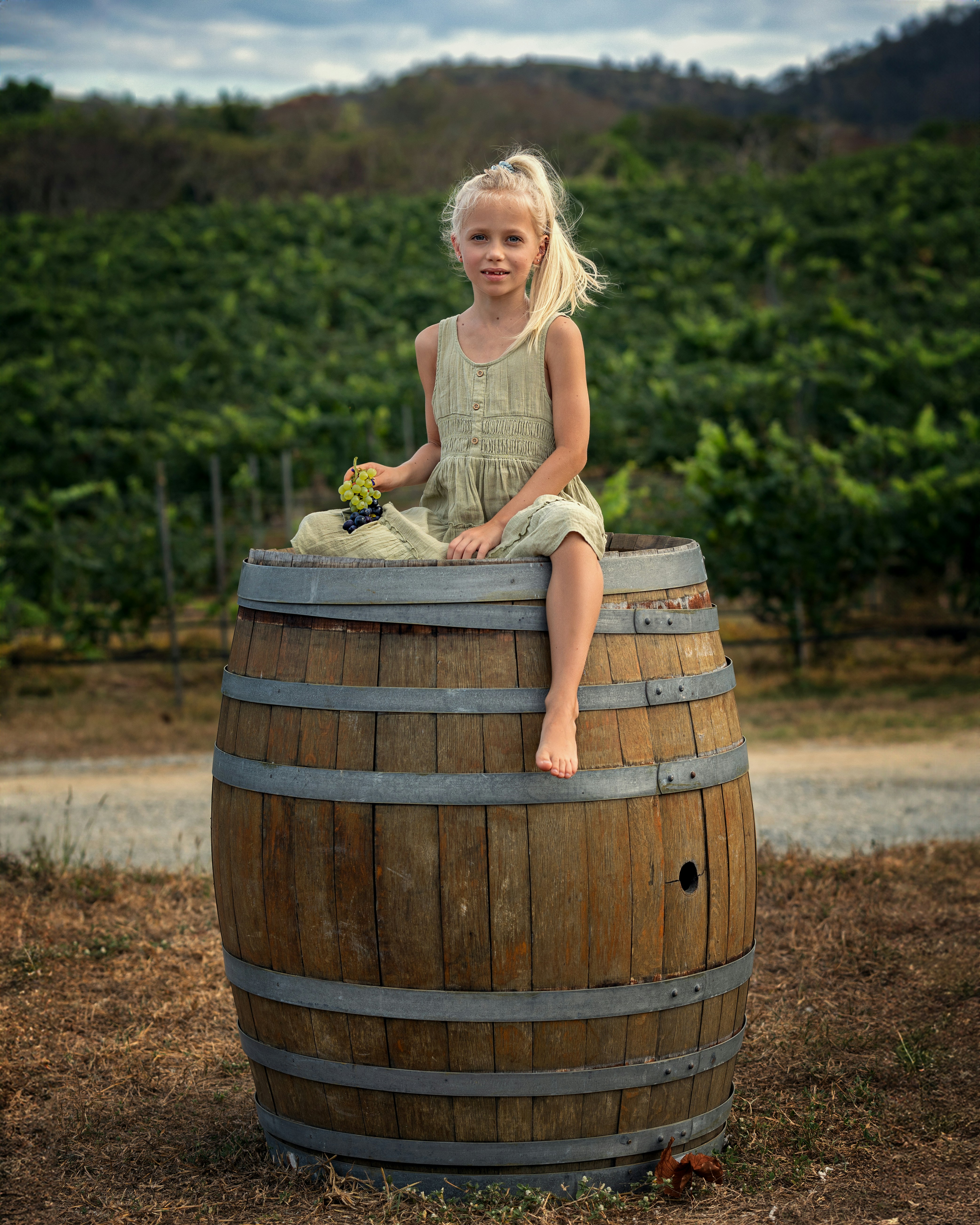 a little girl sitting on top of a wooden barrel