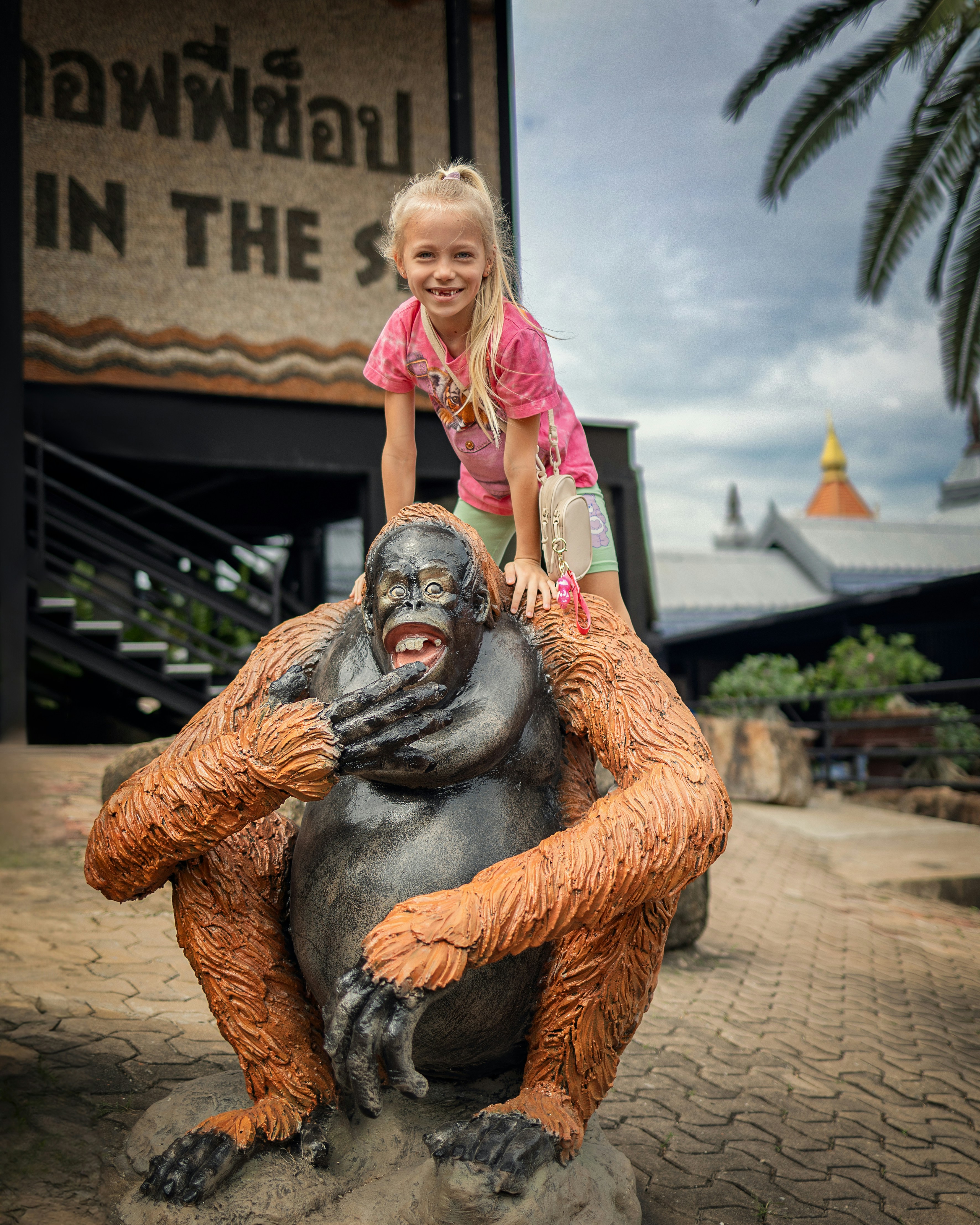 a young girl riding on the back of a gorilla statue