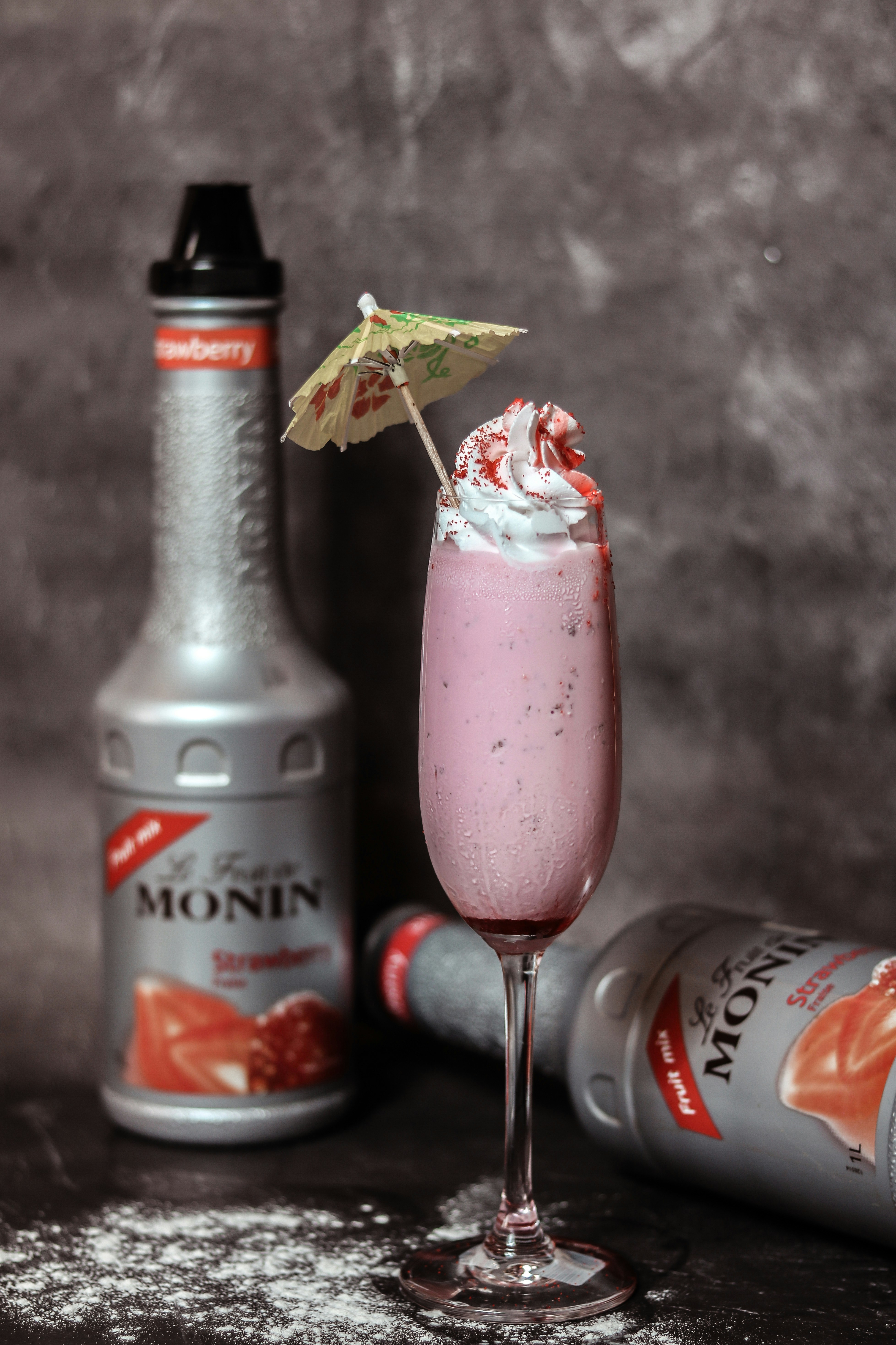 una bebida rosada con crema batida y un paraguas