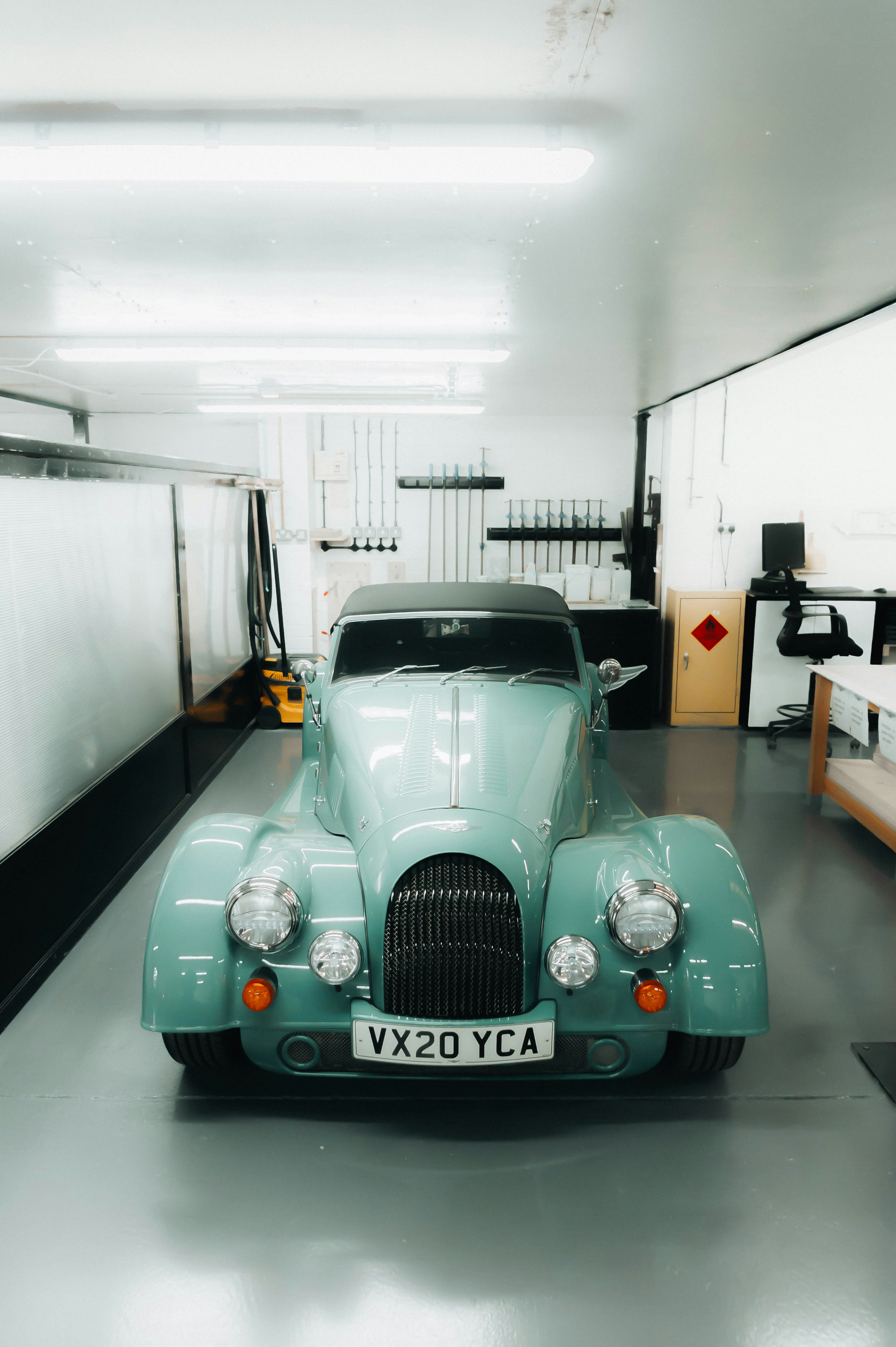 a blue car parked in a garage next to a wall
