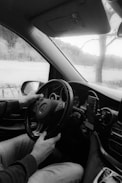 a black and white photo of a man driving a car