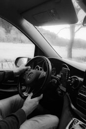 a black and white photo of a man driving a car