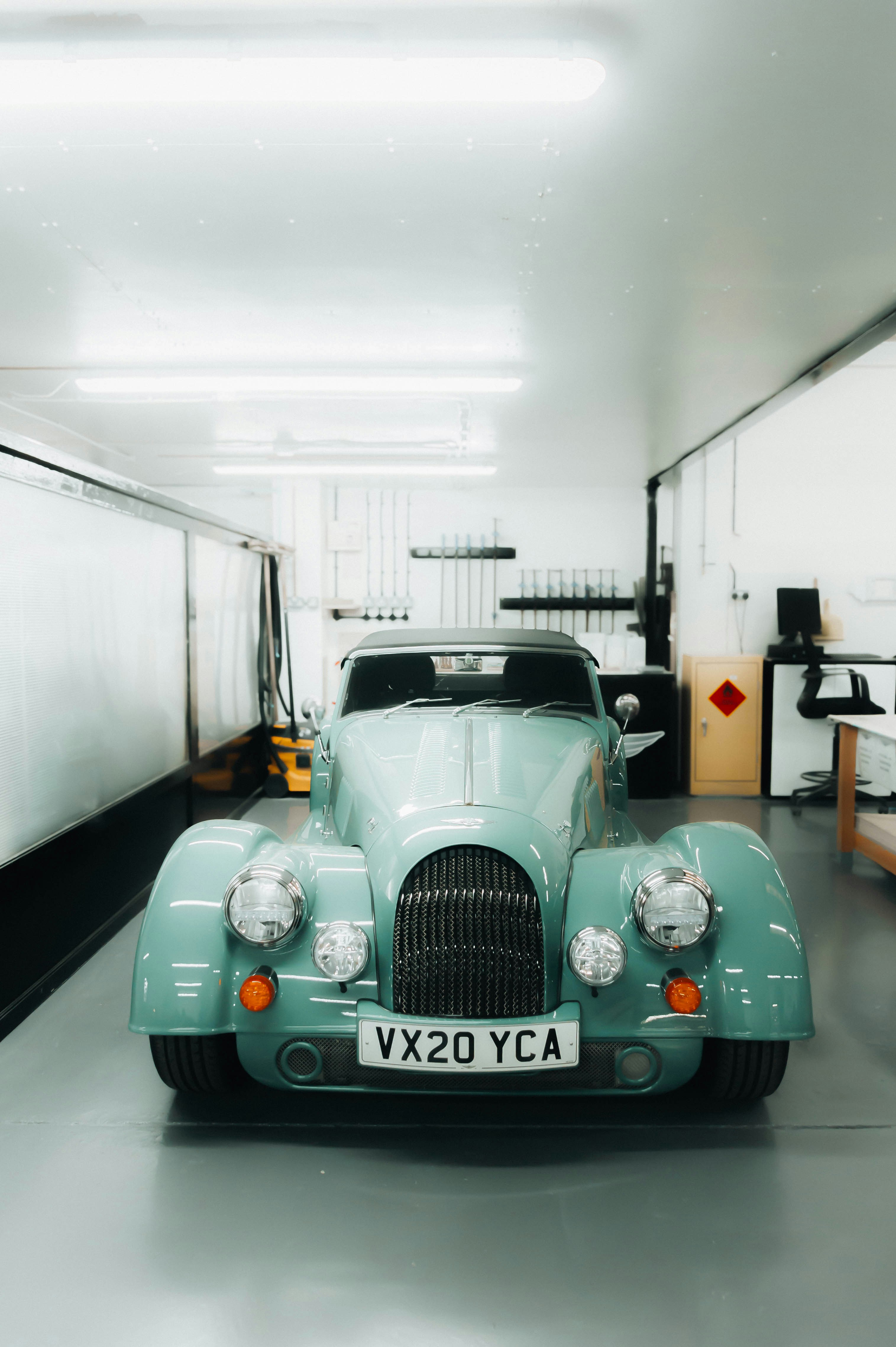 a blue car parked in a garage next to another car