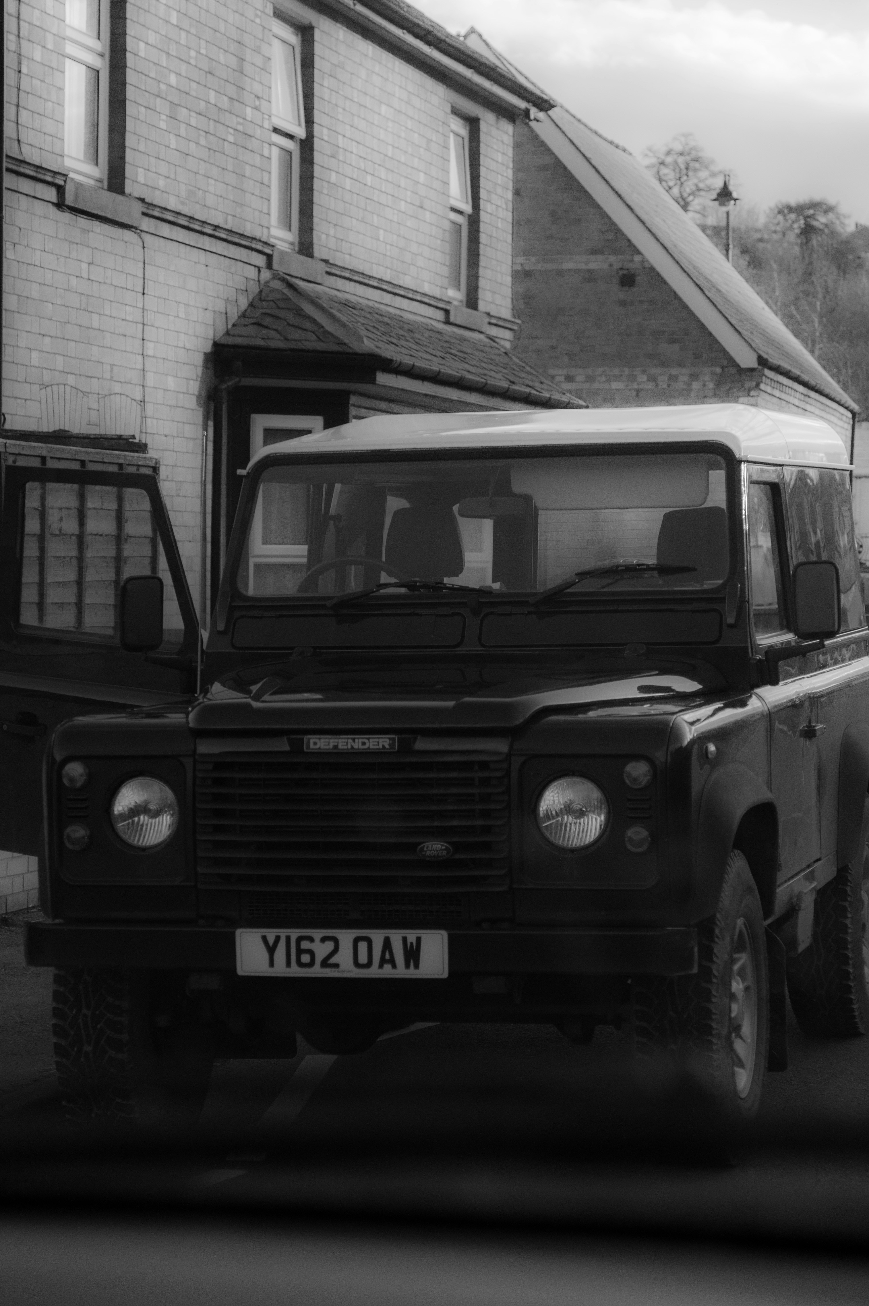 Una foto en blanco y negro de un camión estacionado frente a una casa