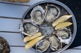 a metal pan filled with oysters and lemon wedges
