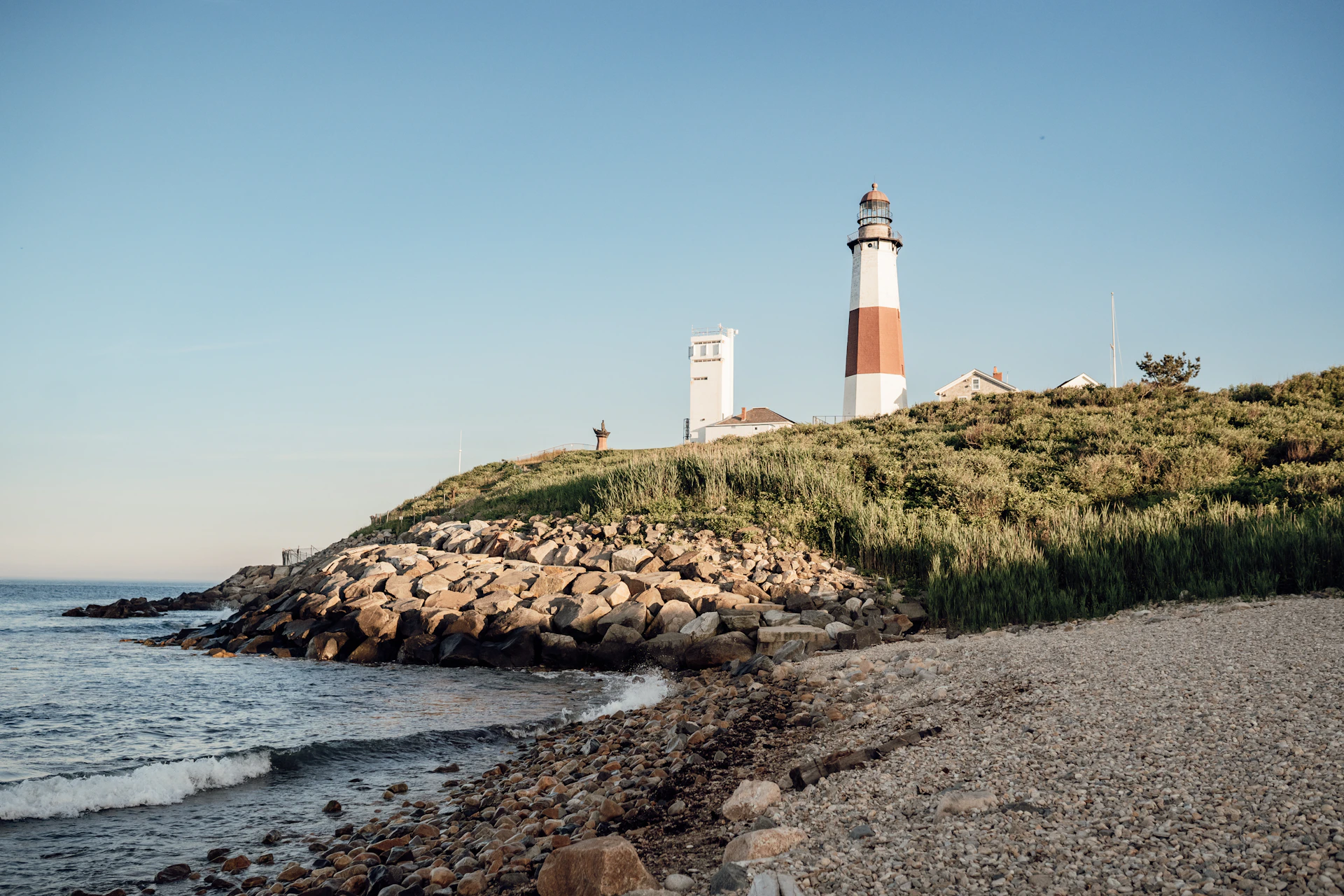 a light house sitting on top of a hill next to the ocean