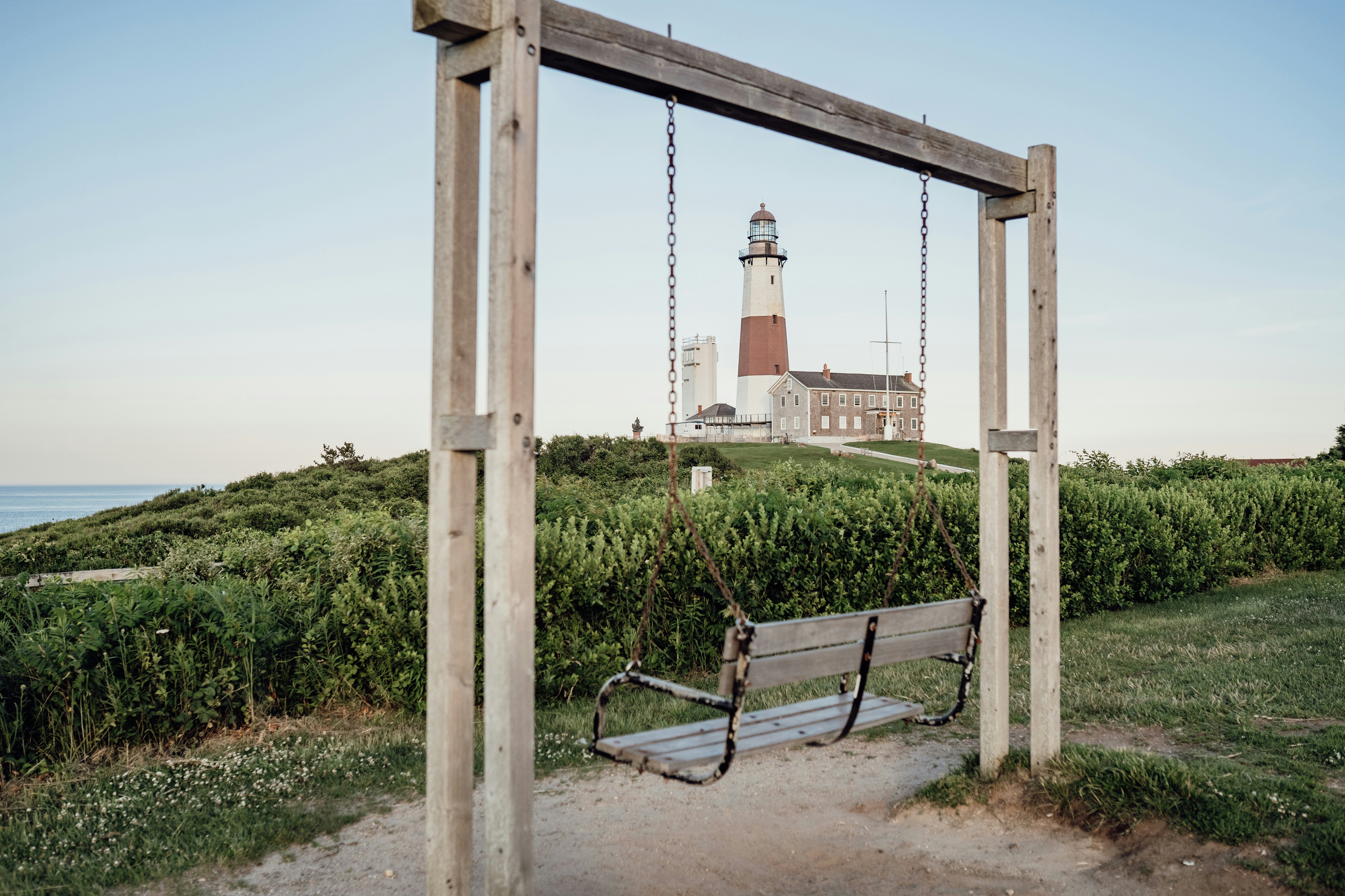 a wooden swing with a lighthouse in the background