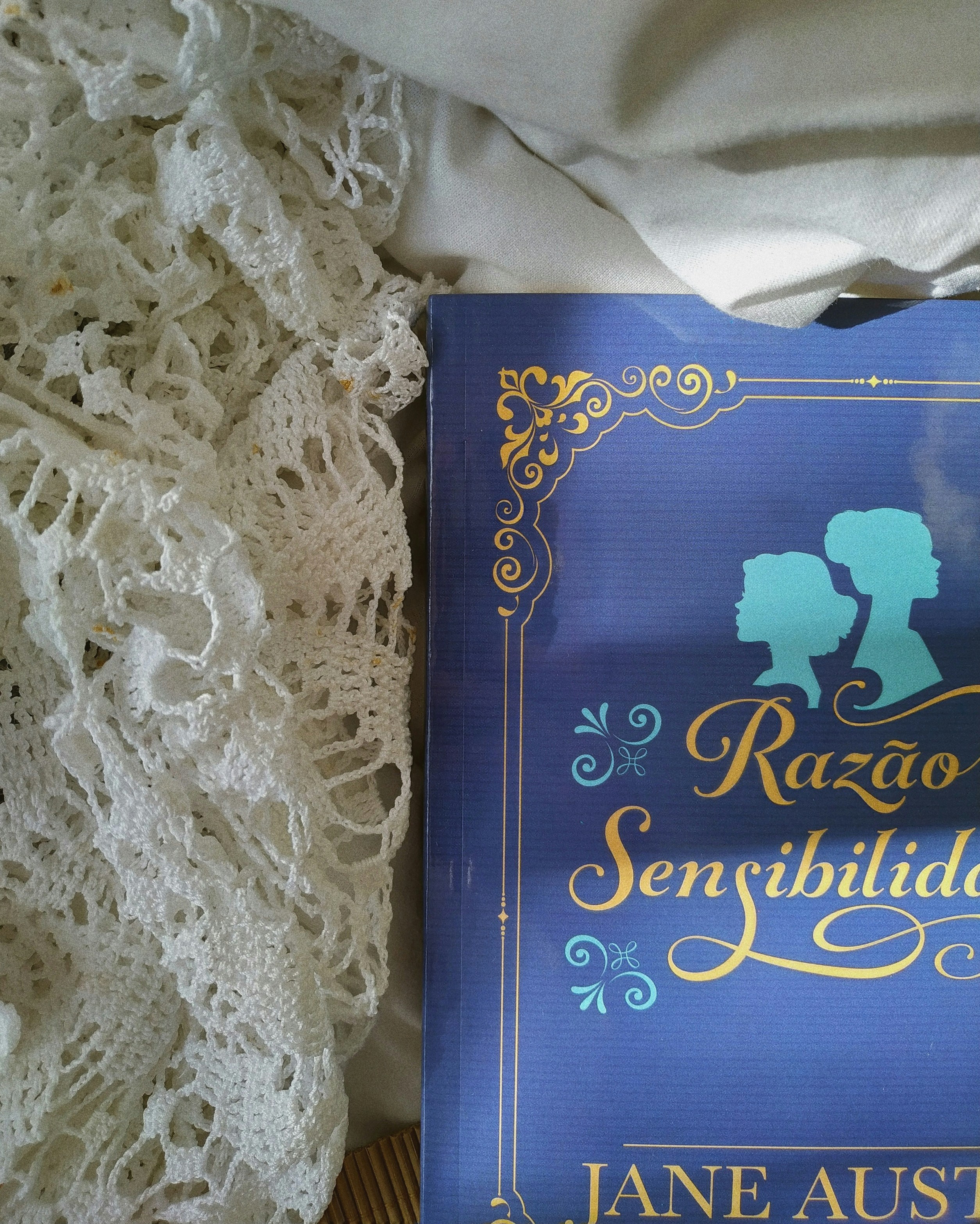a book sitting on top of a bed next to a white lace curtain