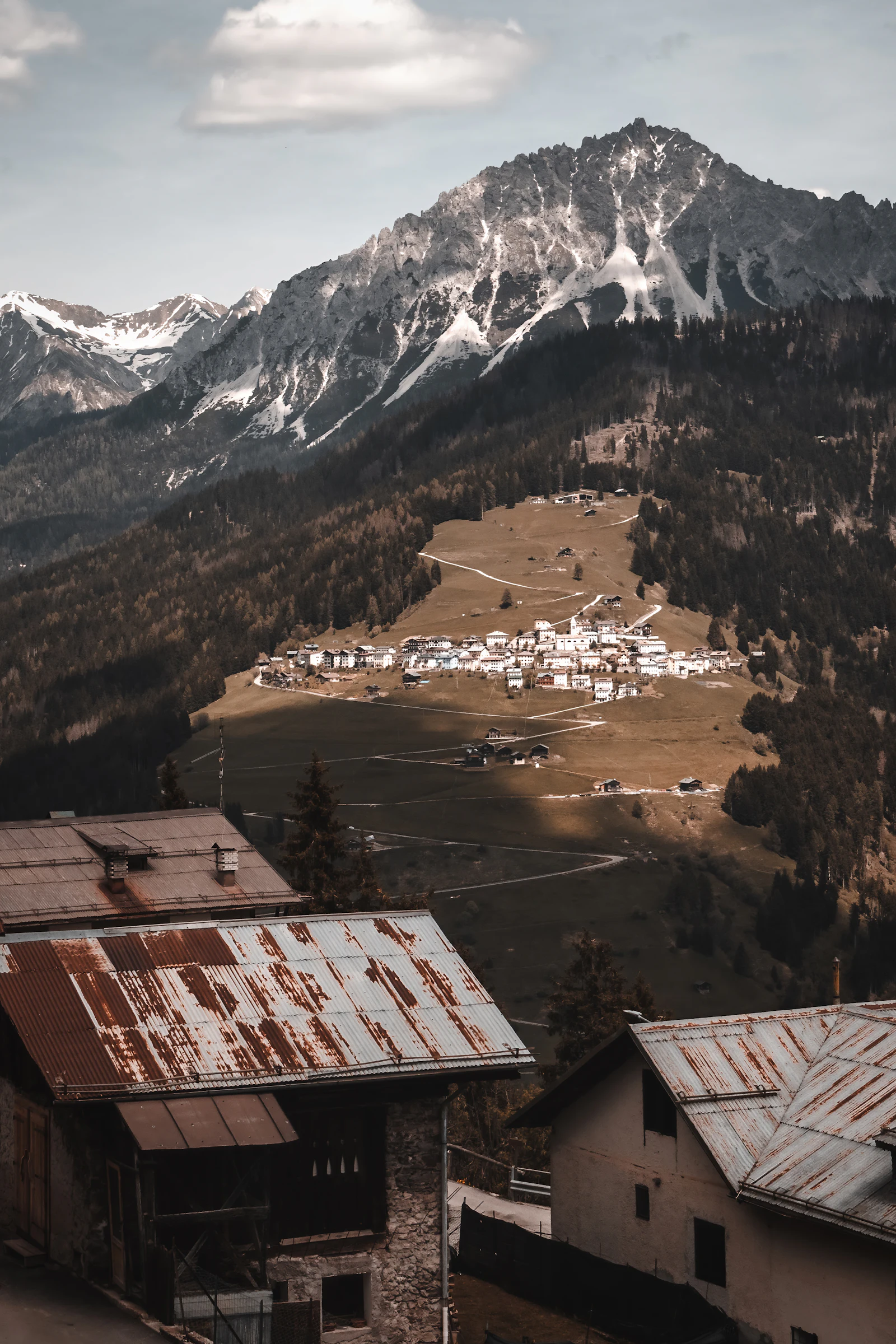Village de montagne au premier plan d'une chaîne de sommets, en été (image d'illustration)