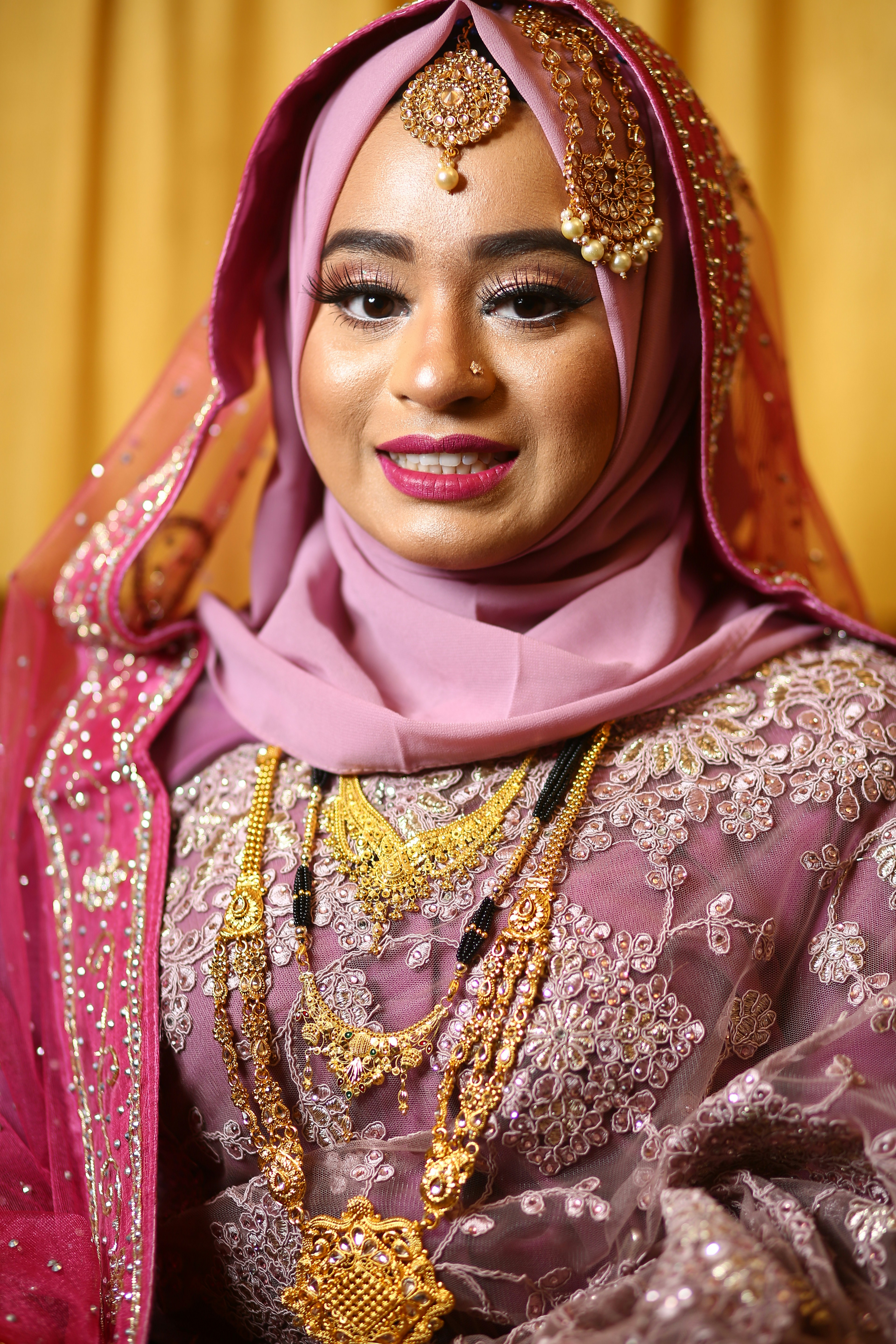 seorang wanita dengan gaun merah muda dan penutup kepala