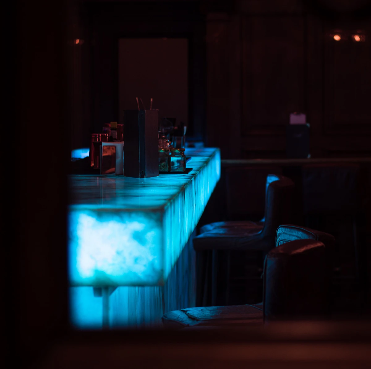 Empty stools at a dimly lit bar