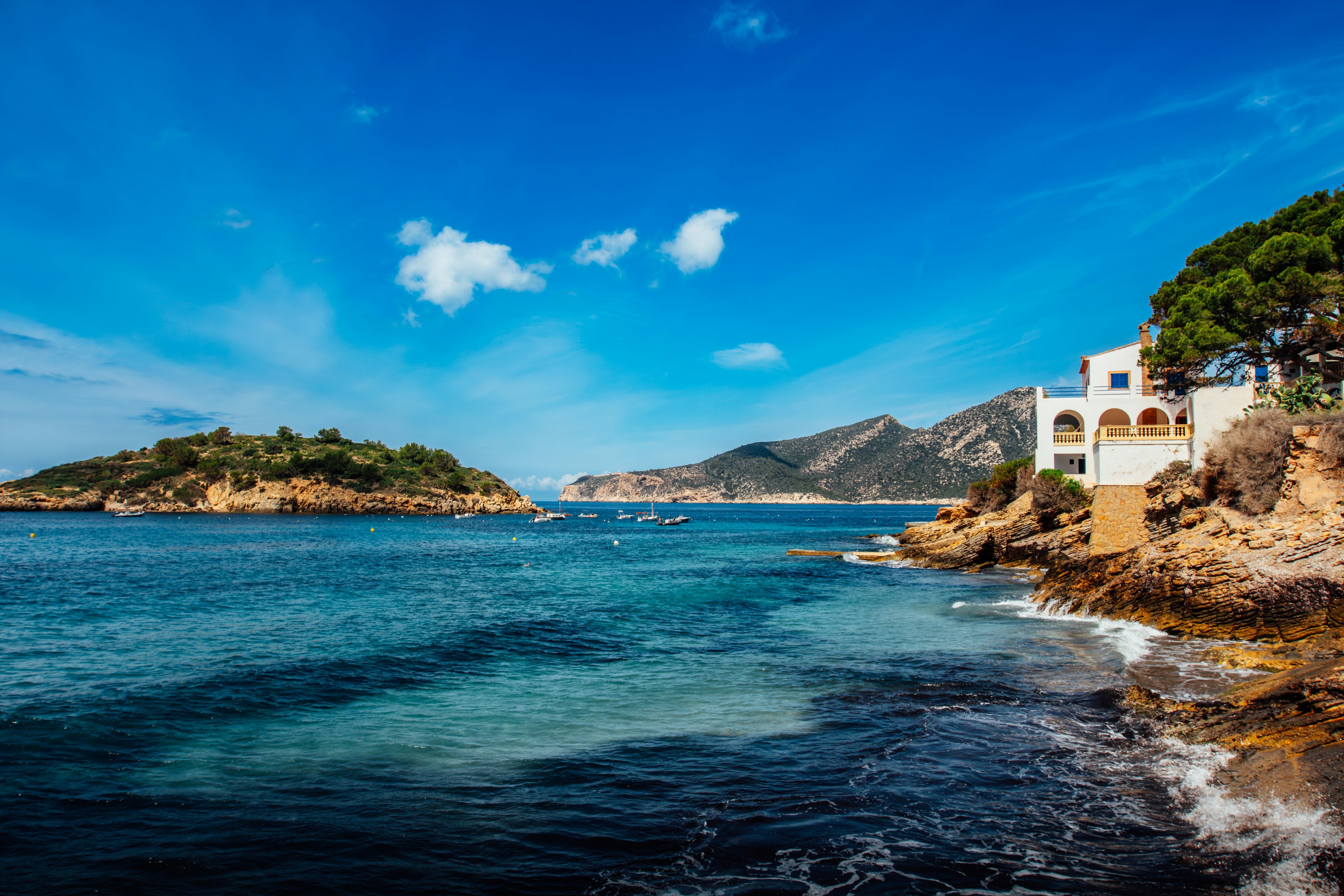 a white house on a rocky cliff overlooking a body of water, The coast and the house - Mallorca