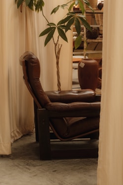 a brown leather chair sitting in front of a window
