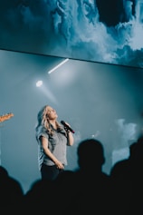 a woman singing into a microphone in front of a crowd