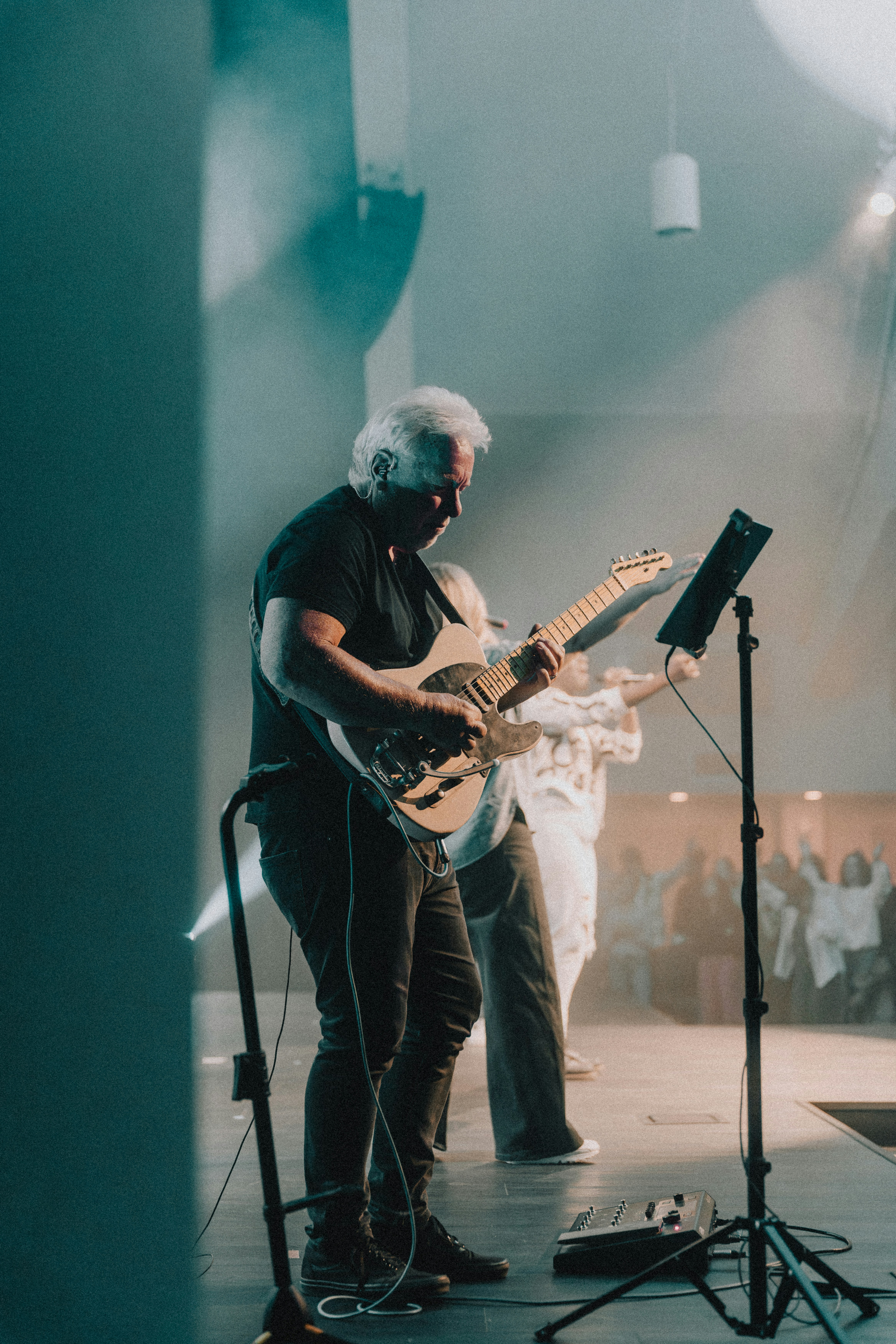 a man playing a guitar in front of a microphone